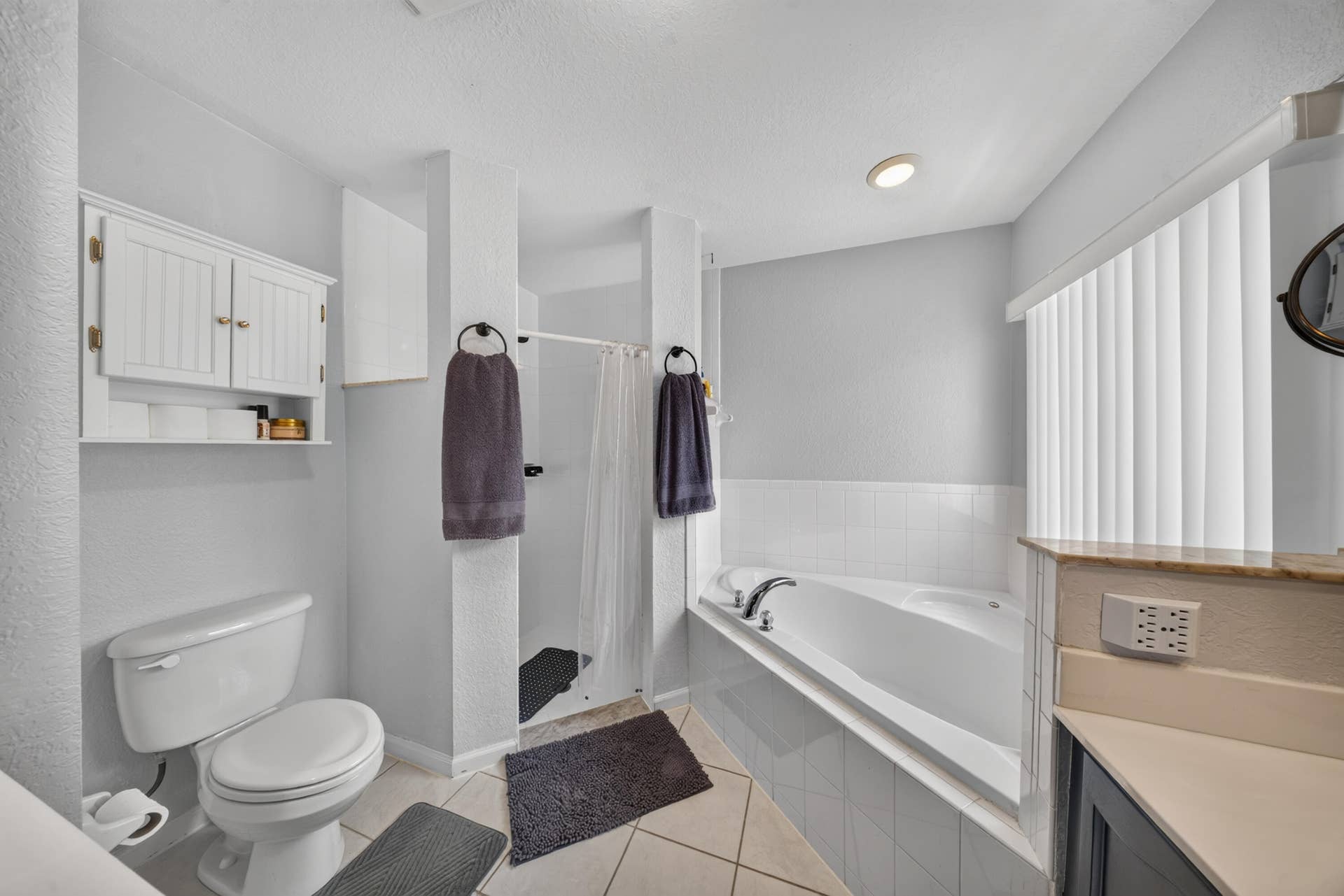 3274 SW CRUMPACKER Street, Port St Lucie, FL 34953 Built-in soaking tub, walk-in shower, wall-mounted storage cabinet, and tiled flooring