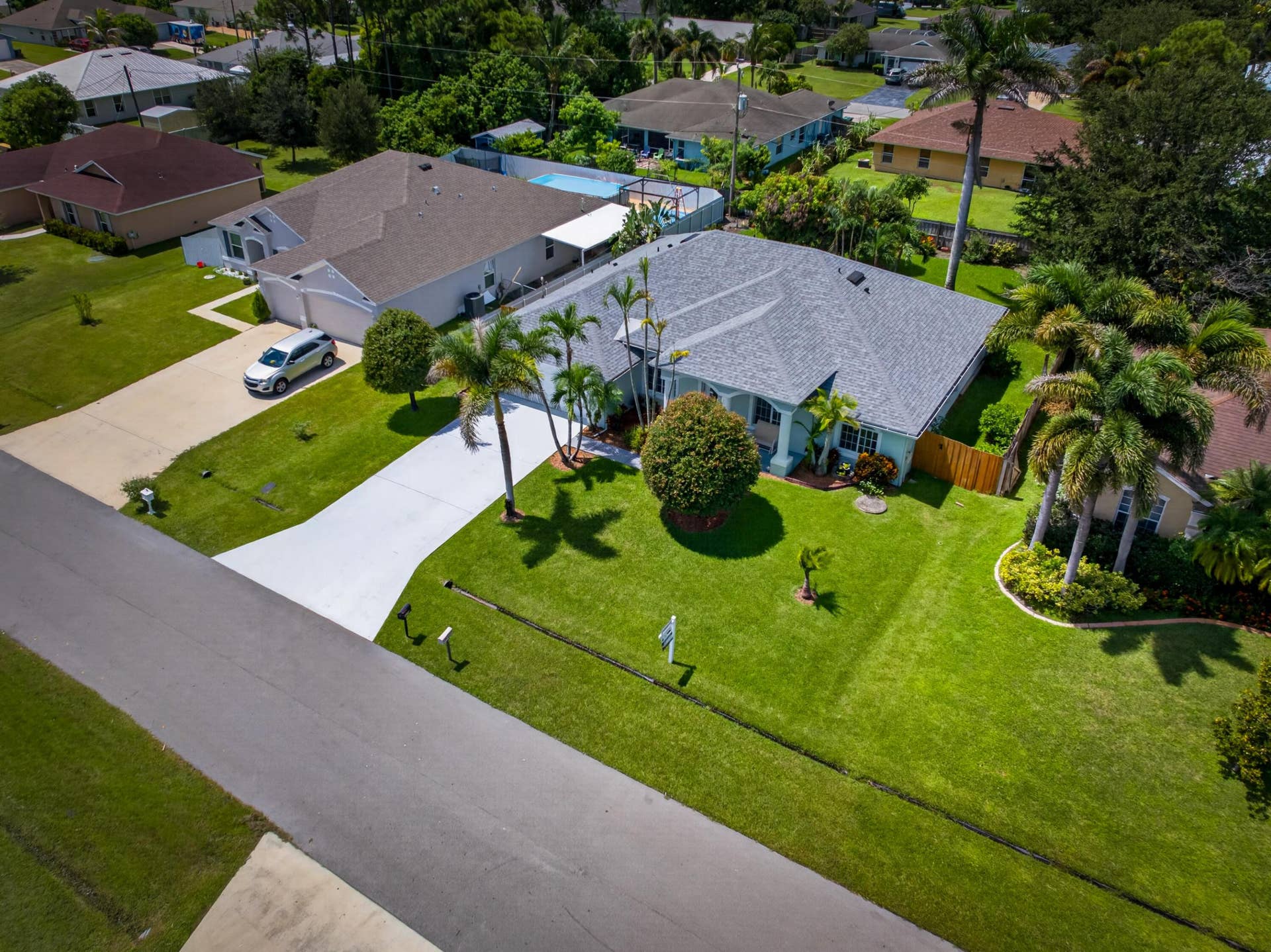 3274 SW CRUMPACKER Street, Port St Lucie, FL 34953 Paved driveway, attached garage, well-maintained lawn, mature landscaping, and privacy fencing
