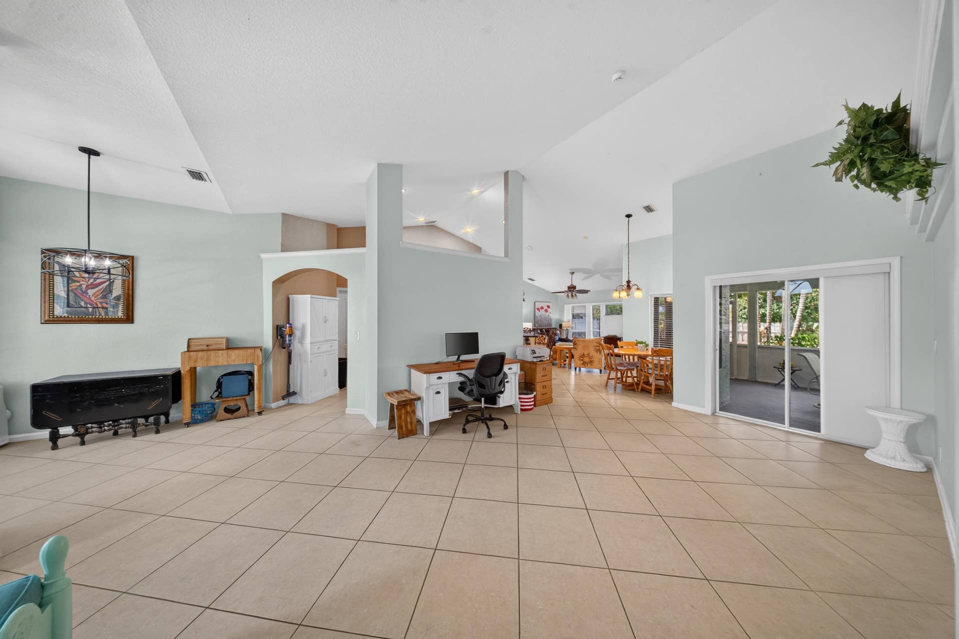3274 SW CRUMPACKER Street, Port St Lucie, FL 34953 Vaulted ceiling, tiled flooring, arched doorway, sliding glass door, pendant lighting