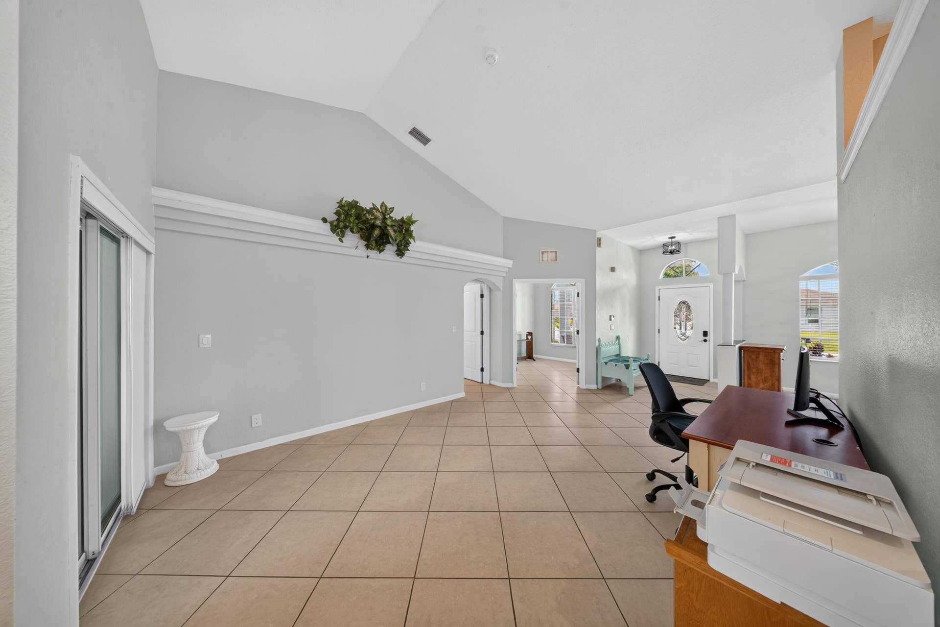 3274 SW CRUMPACKER Street, Port St Lucie, FL 34953 Vaulted ceilings, neutral wall tones, ceramic tile flooring, decorative architectural ledge, and sliding glass doors