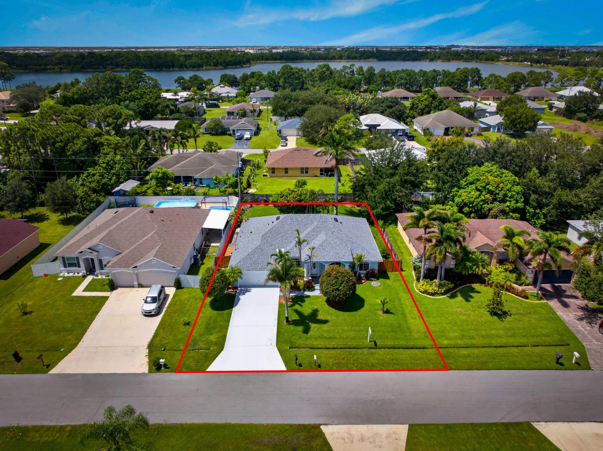 3274 SW CRUMPACKER Street, Port St Lucie, FL 34953 Single-story residential structure with a light-colored roof, front lawn, and paved driveway