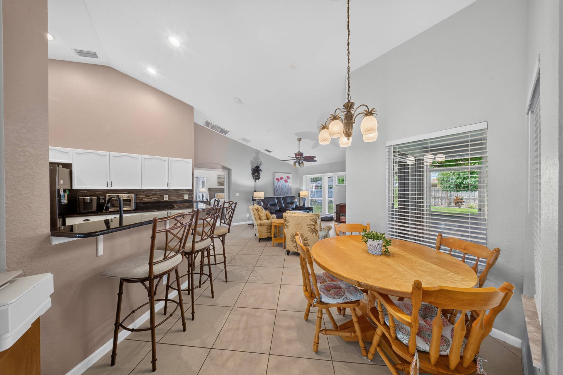 3274 SW CRUMPACKER Street, Port St Lucie, FL 34953 Vaulted ceilings, tiled flooring, white cabinetry, black countertops, and a decorative chandelier