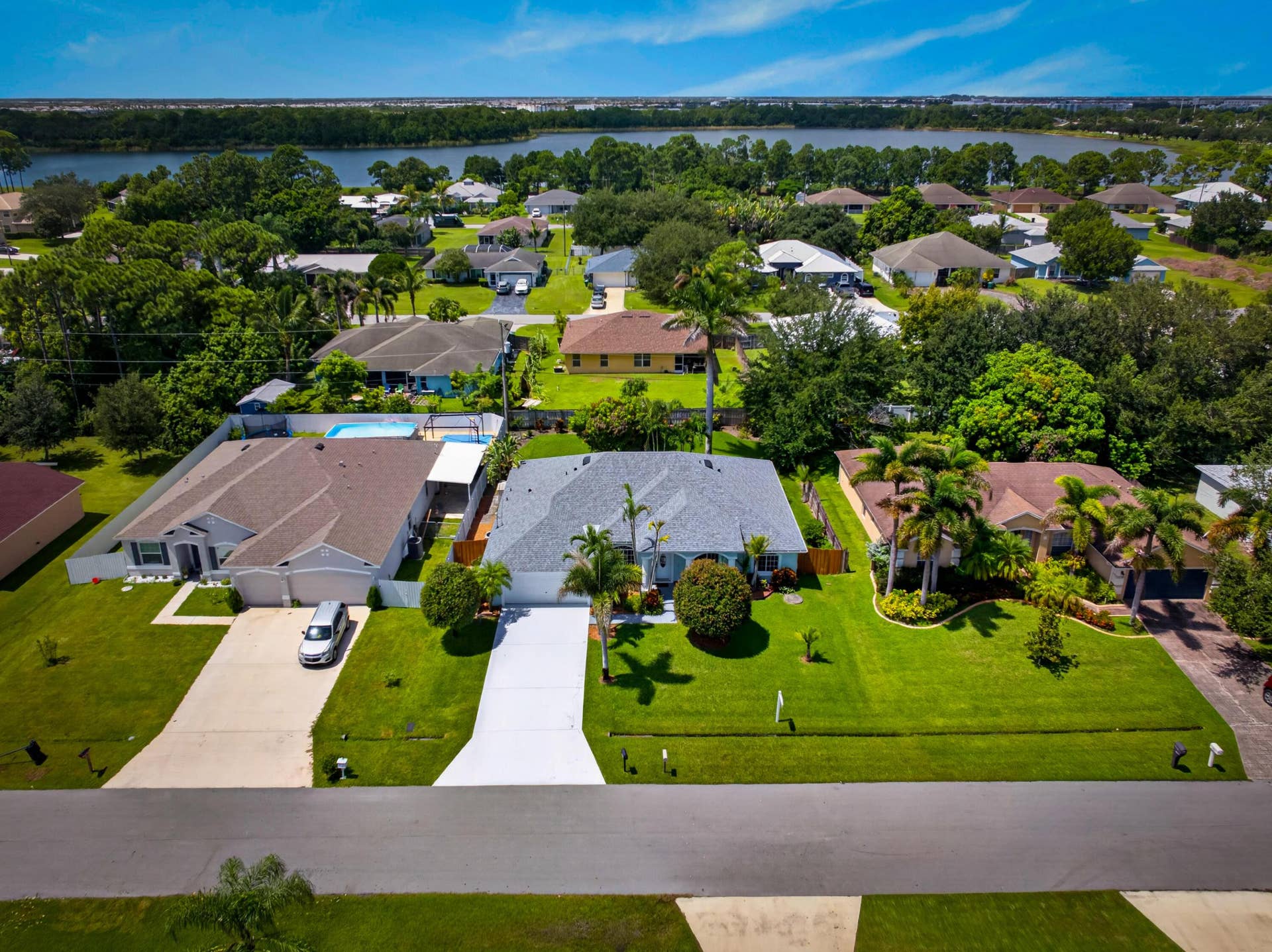 3274 SW CRUMPACKER Street, Port St Lucie, FL 34953 Aerial perspective showcasing a residential street, manicured lawns, and mature landscaping