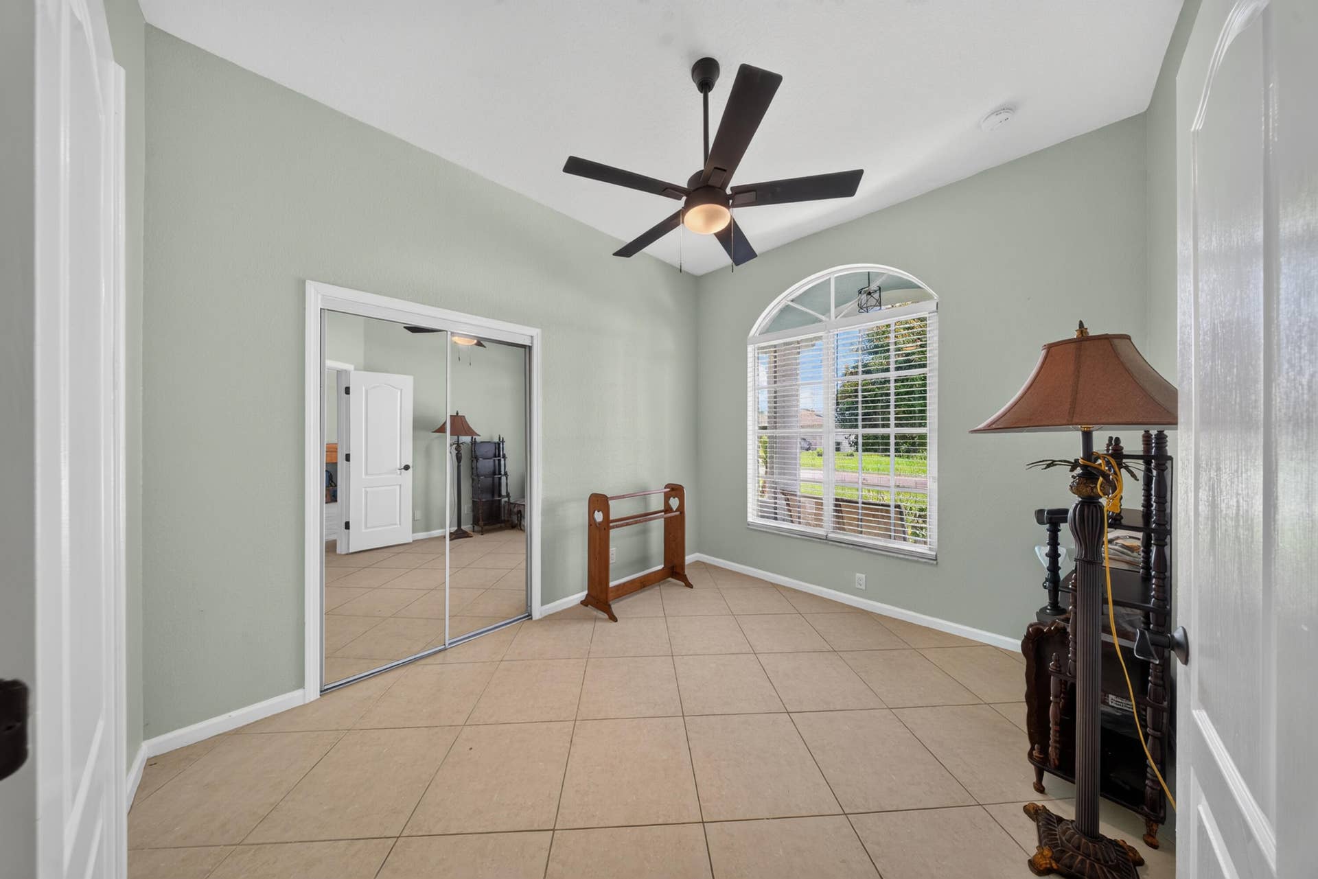 3274 SW CRUMPACKER Street, Port St Lucie, FL 34953 Vaulted ceiling with a ceiling fan, arched window, tiled flooring, and mirrored closet doors