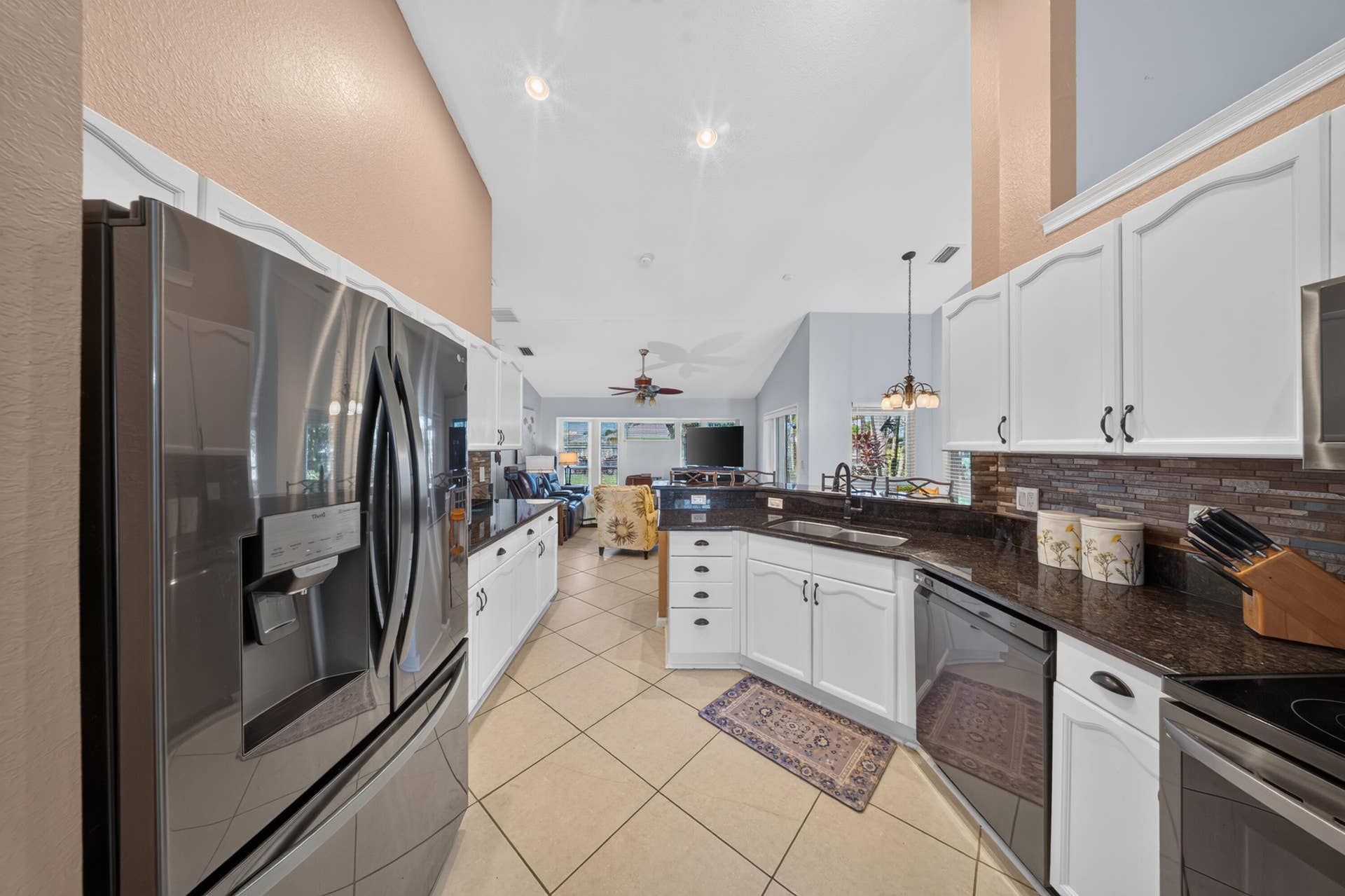 3274 SW CRUMPACKER Street, Port St Lucie, FL 34953 Kitchen featuring vaulted ceilings, stainless steel appliances, white cabinetry, dark stone countertops, and a mosaic tile backsplash