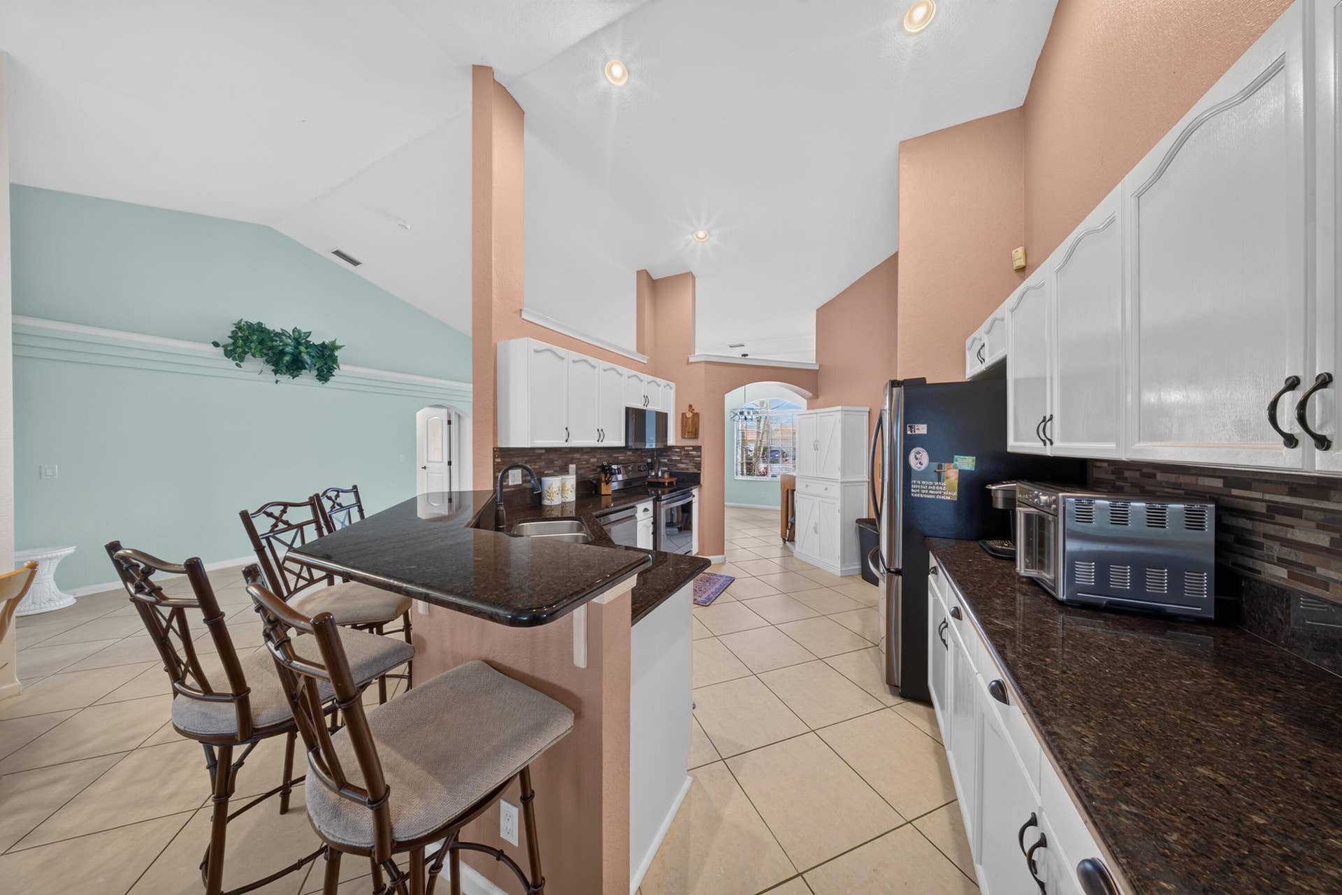 3274 SW CRUMPACKER Street, Port St Lucie, FL 34953 Kitchen featuring white cabinetry, dark countertops, tile flooring, a tile backsplash, and a breakfast bar