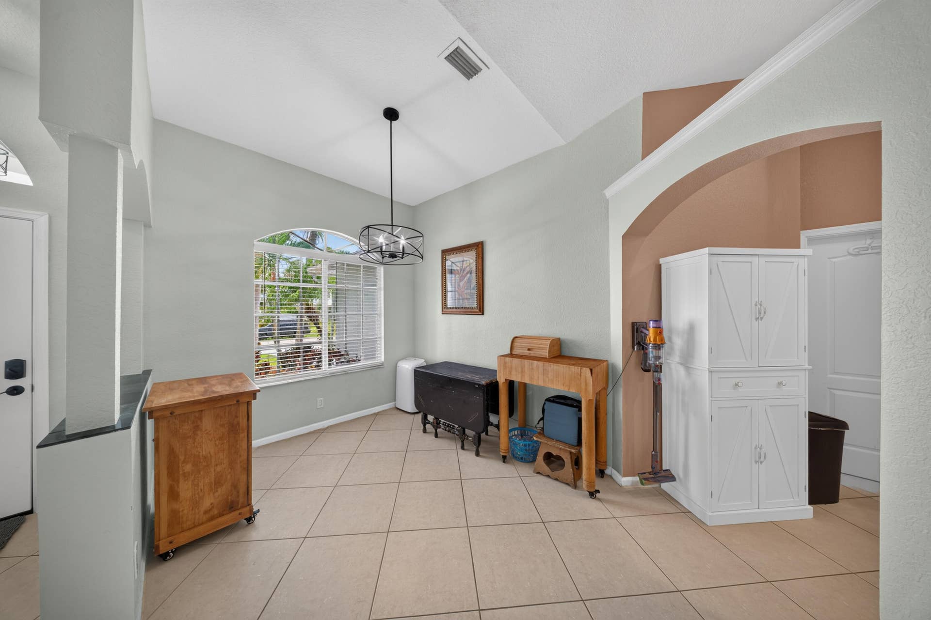 3274 SW CRUMPACKER Street, Port St Lucie, FL 34953 Vaulted ceilings, arched wall opening, tiled flooring, an arched window, and a contemporary chandelier