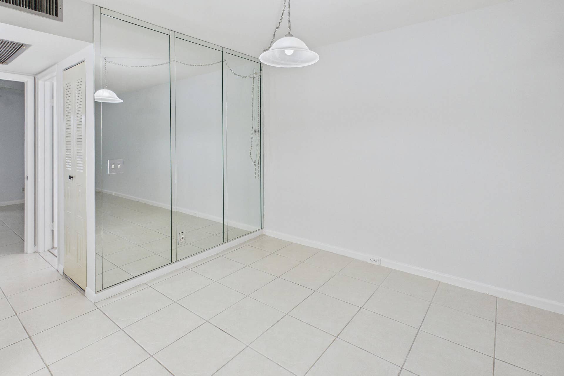13155 SW 7TH Court, #103E, Pembroke Pines, FL 33027 Tile flooring, mirrored wall, white walls, and a ceiling-mounted light fixture.