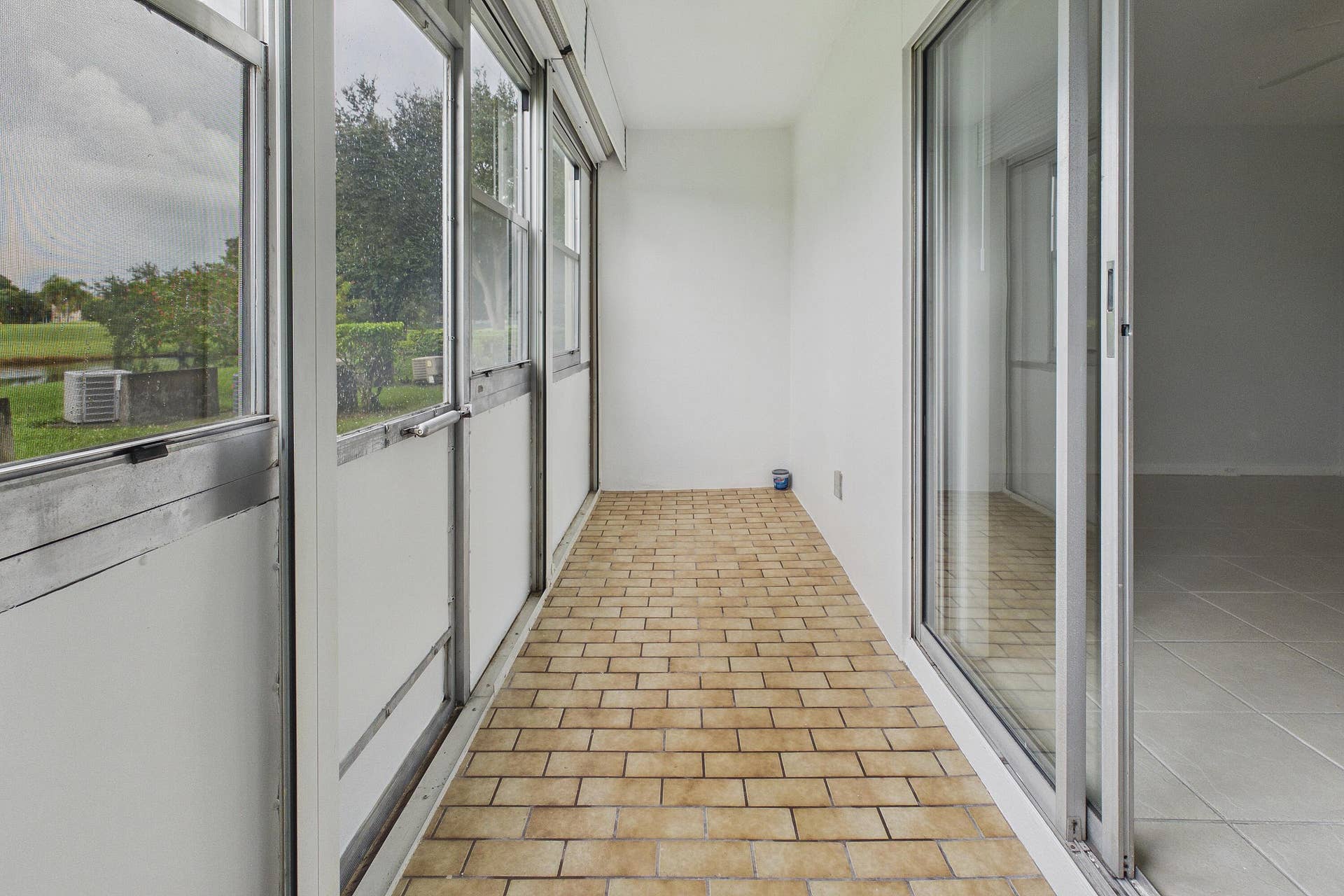 13155 SW 7TH Court, #103E, Pembroke Pines, FL 33027 Enclosed and covered patio with brick-patterned flooring and a sliding glass door
