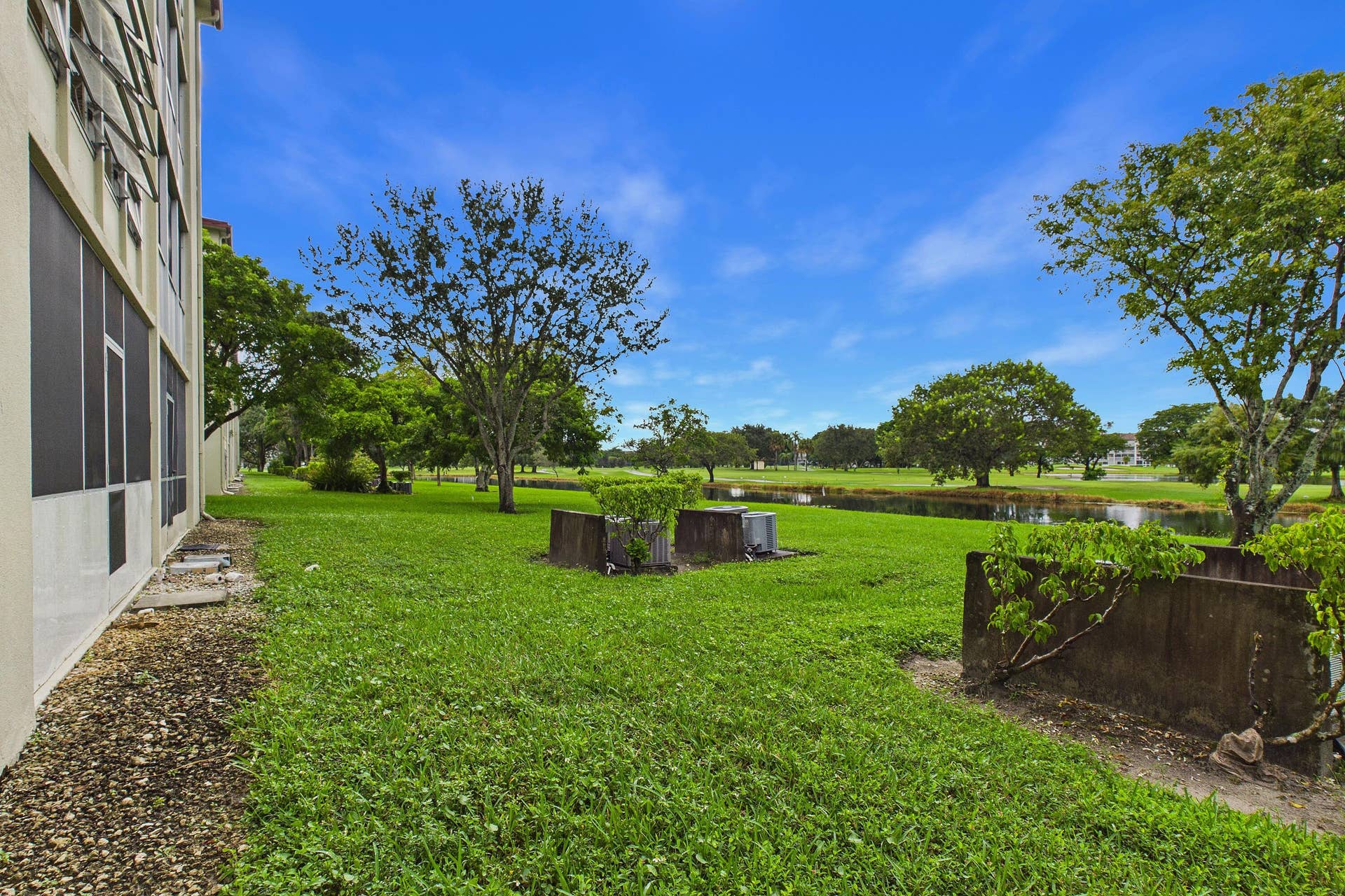 13155 SW 7TH Court, #103E, Pembroke Pines, FL 33027 Expansive green space featuring mature trees and a tranquil water feature