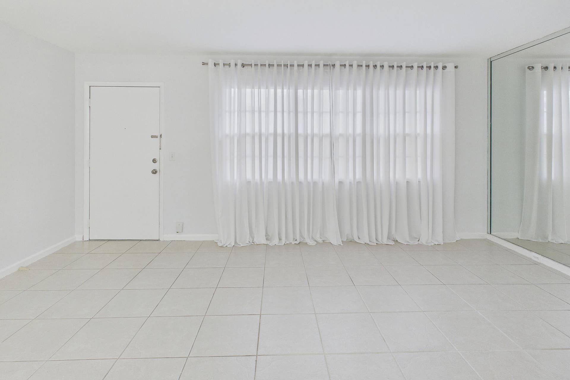 13155 SW 7TH Court, #103E, Pembroke Pines, FL 33027 Tile flooring, white walls, full-length mirror, window with sheer curtains, solid entry door