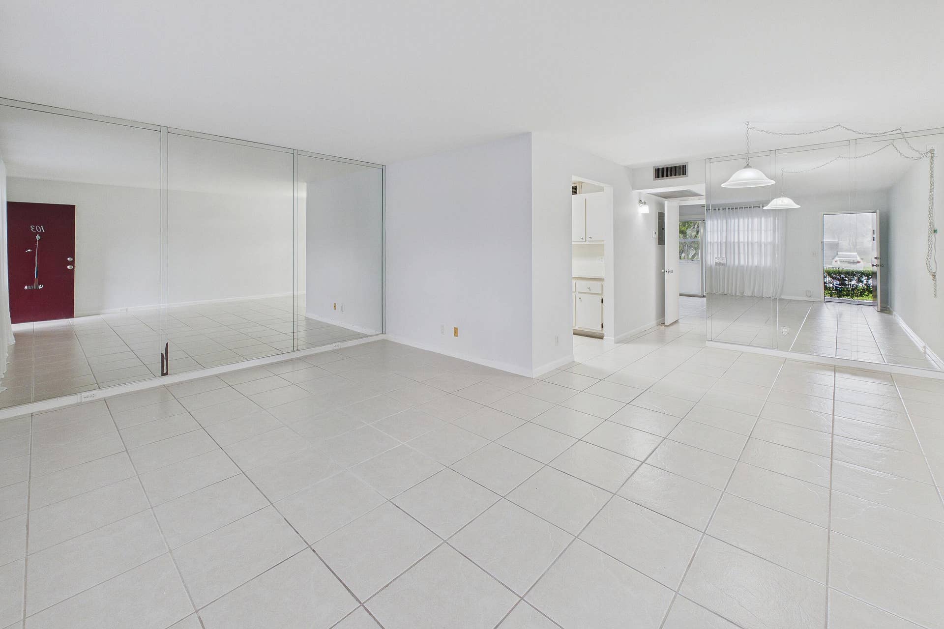 13155 SW 7TH Court, #103E, Pembroke Pines, FL 33027 Spacious main living area featuring light-toned tile flooring, and mirrored accent walls.