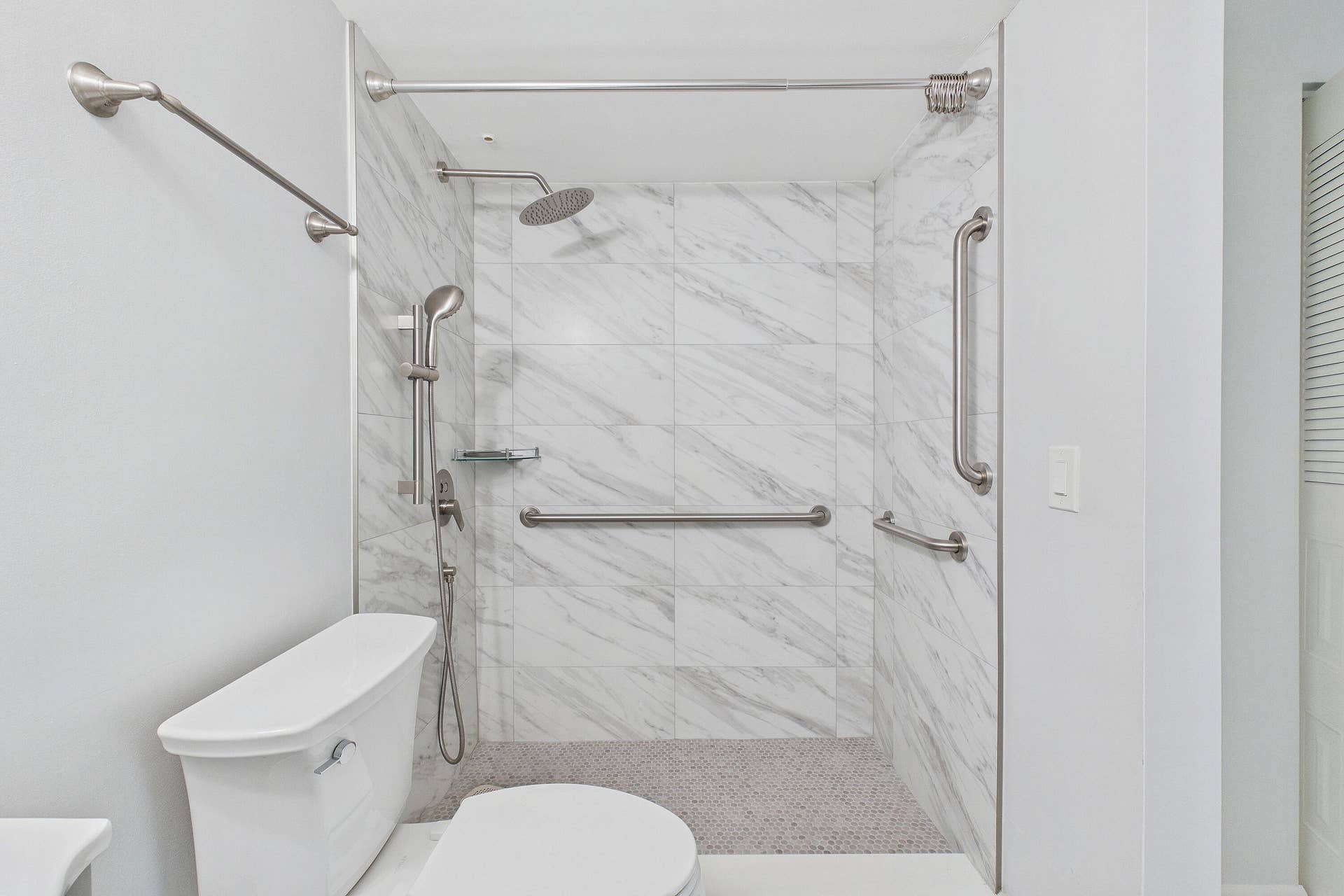 13155 SW 7TH Court, #103E, Pembroke Pines, FL 33027 Renovated handicap accessible walk-in shower featuring marble-look wall tiles, a rainfall showerhead, and a handheld shower fixture