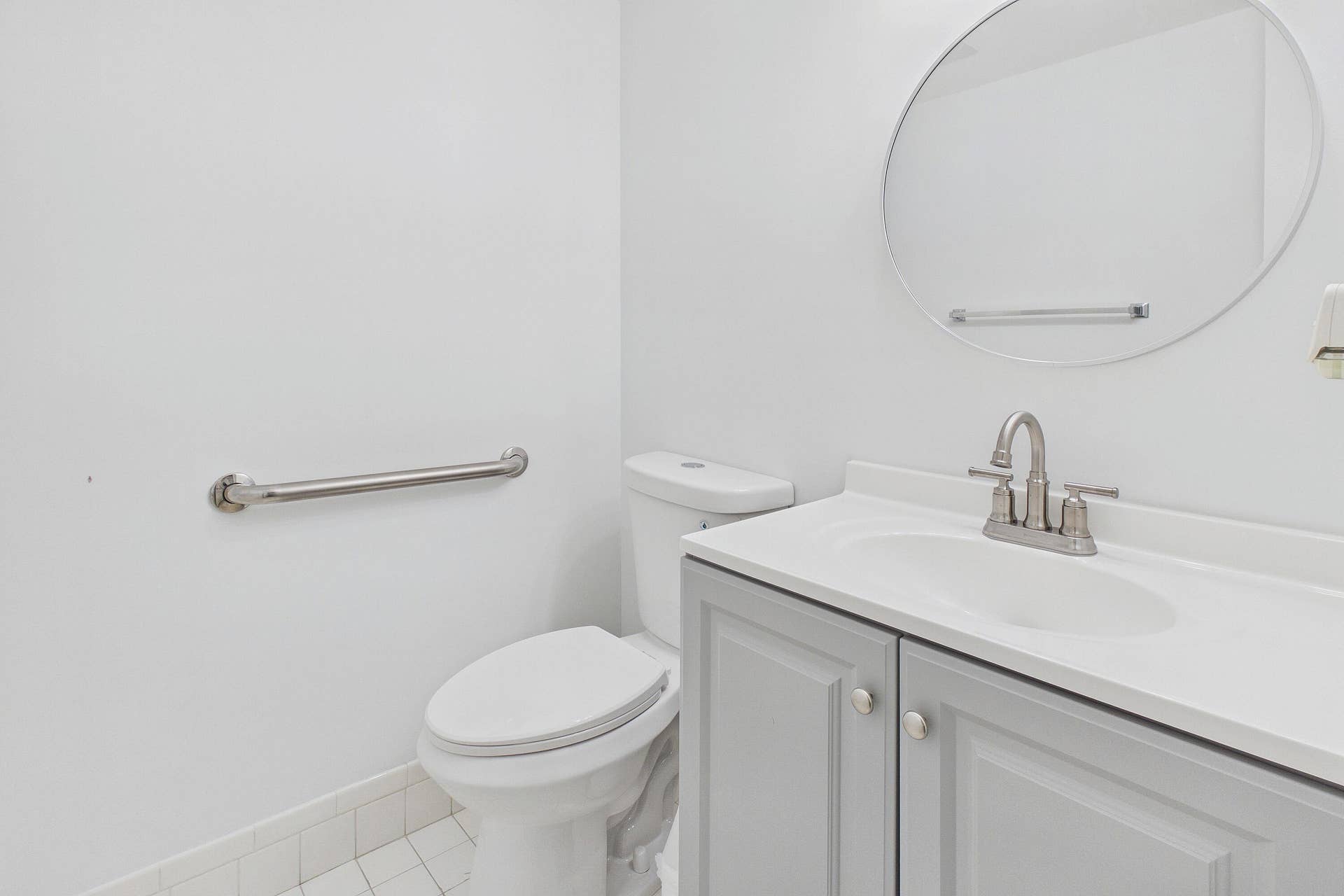 13155 SW 7TH Court, #103E, Pembroke Pines, FL 33027 Bathroom featuring a vanity with a light gray cabinet, white countertop, integrated sink, and a circular mirror
