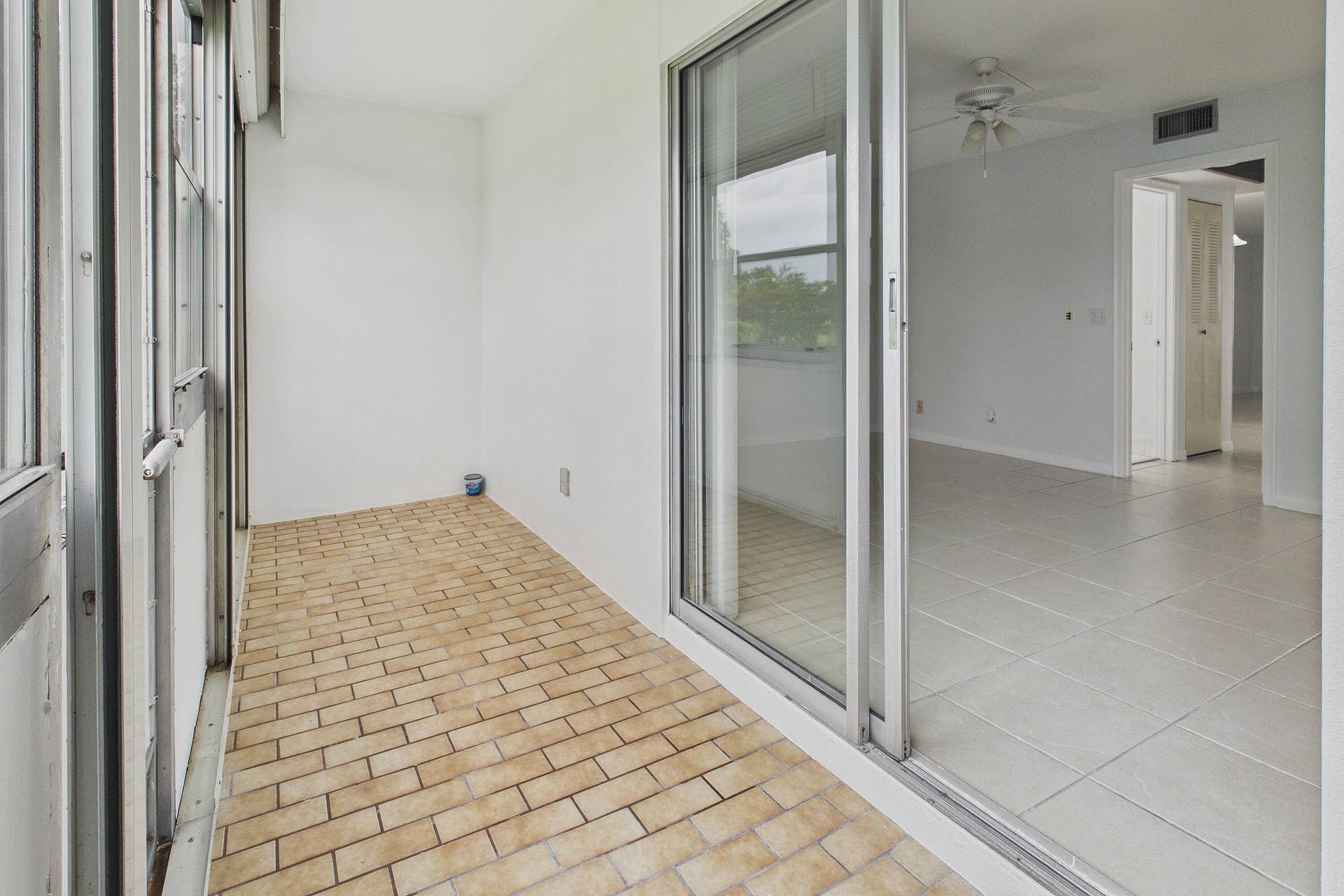 13155 SW 7TH Court, #103E, Pembroke Pines, FL 33027 Enclosed and covered patio with brick-pattern flooring and white walls, offering access to an interior space with light-toned tile flooring and a ceiling fan