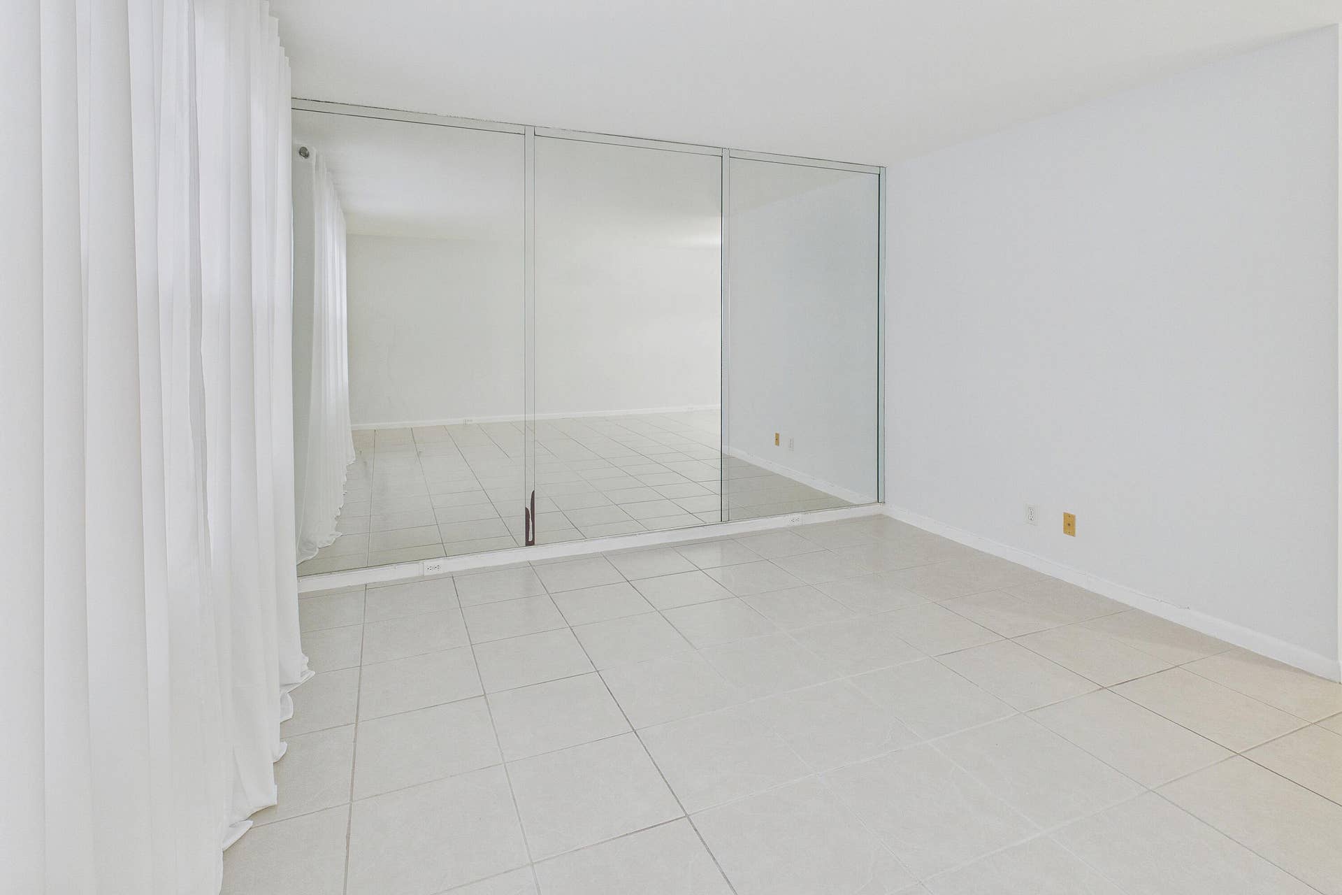 13155 SW 7TH Court, #103E, Pembroke Pines, FL 33027 White tile flooring, full-height mirrored wall, and sheer white curtains.