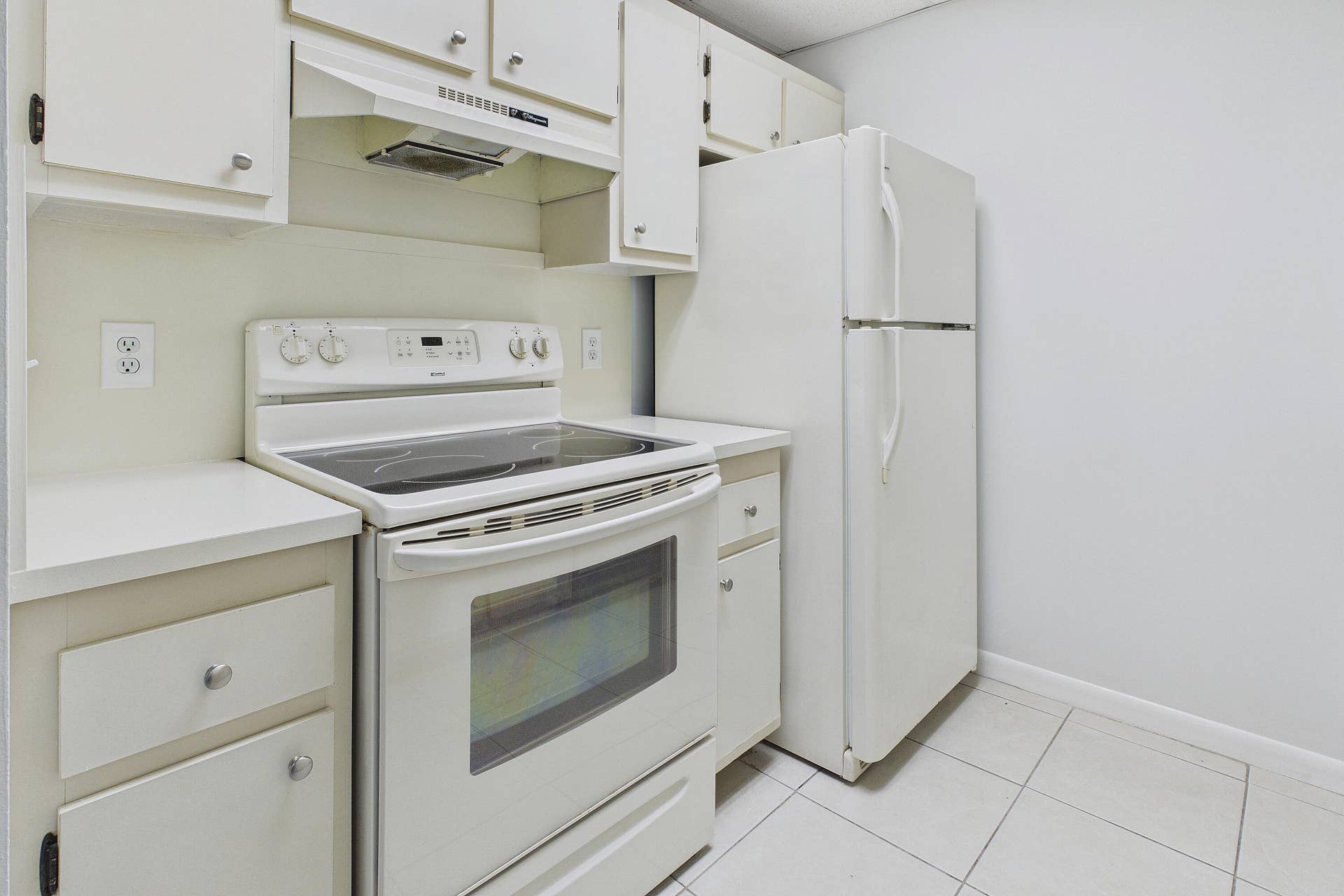 13155 SW 7TH Court, #103E, Pembroke Pines, FL 33027 Kitchen featuring white cabinetry, solid surface countertops, white refrigerator, electric range, and tiled flooring
