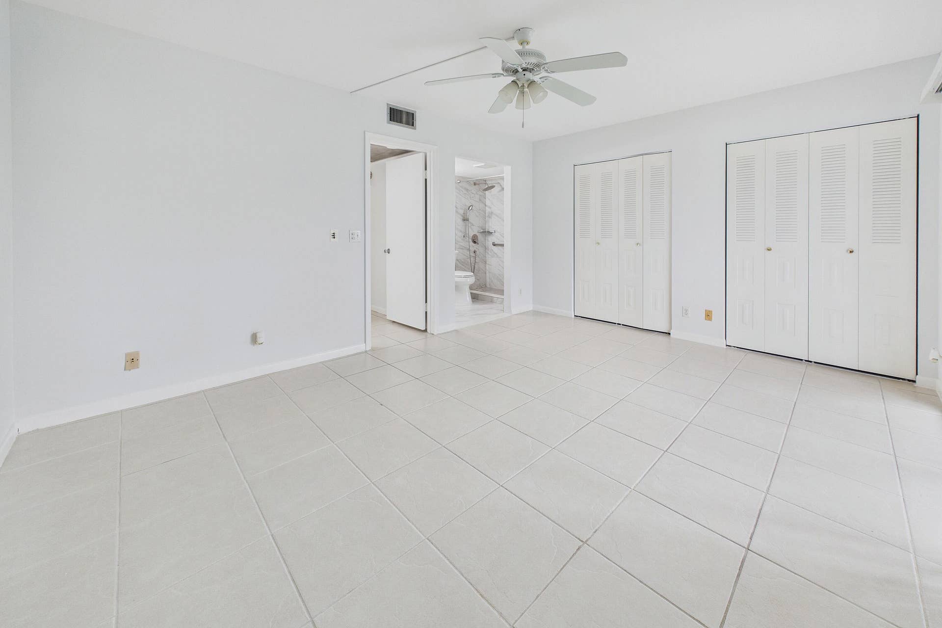 13155 SW 7TH Court, #103E, Pembroke Pines, FL 33027 Light-toned tile flooring, two louvered bifold closet doors, a ceiling fan, and a neutral wall color