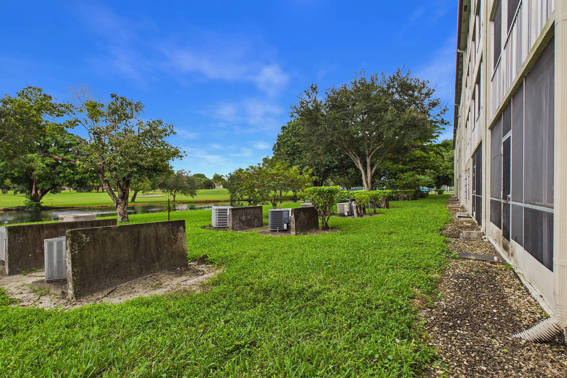 13155 SW 7TH Court, #103E, Pembroke Pines, FL 33027 Expansive green space featuring mature trees and a tranquil water feature