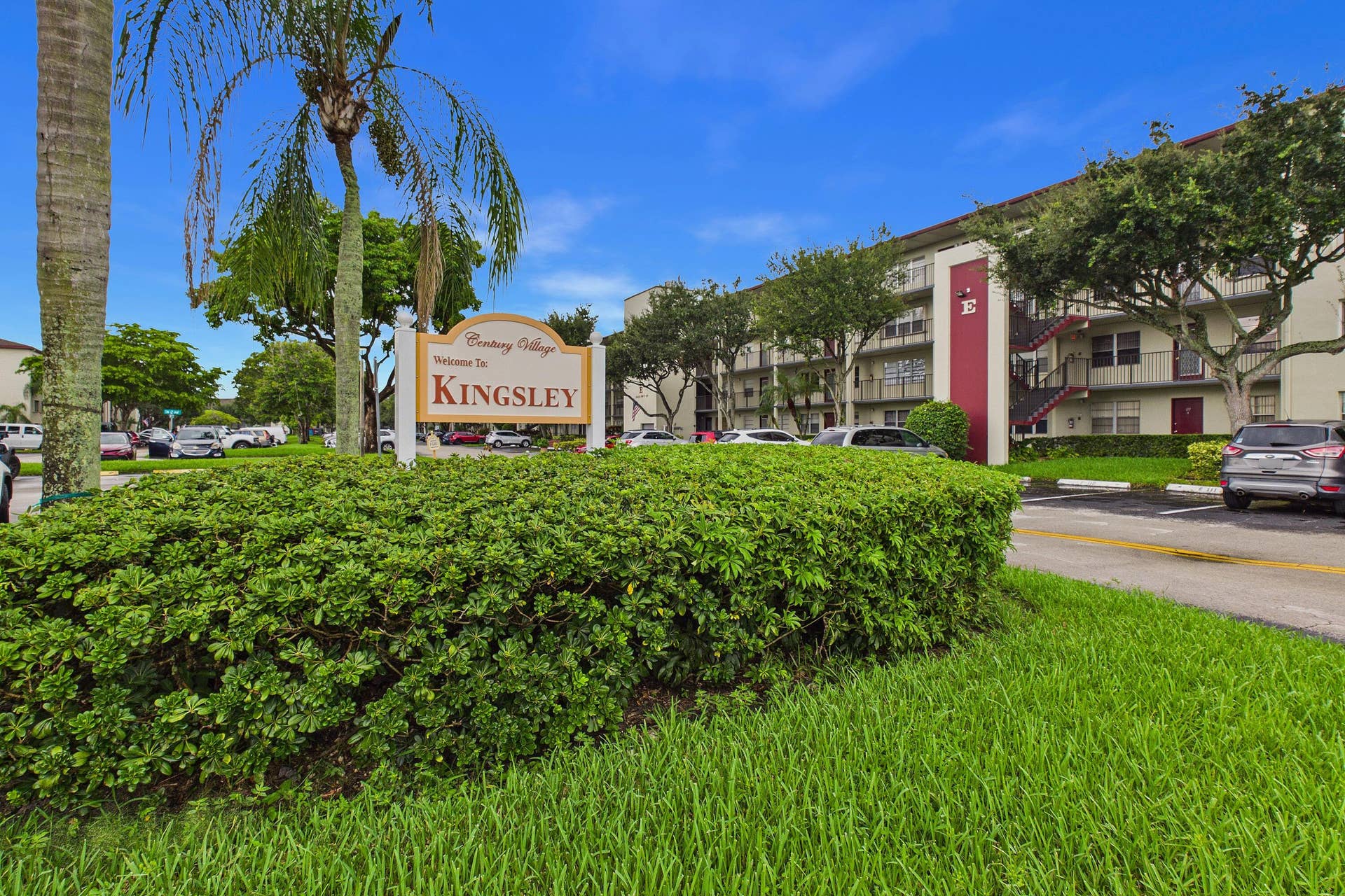 13155 SW 7TH Court, #103E, Pembroke Pines, FL 33027 Building exterior with balconies, a prominent entrance sign, and mature landscaping