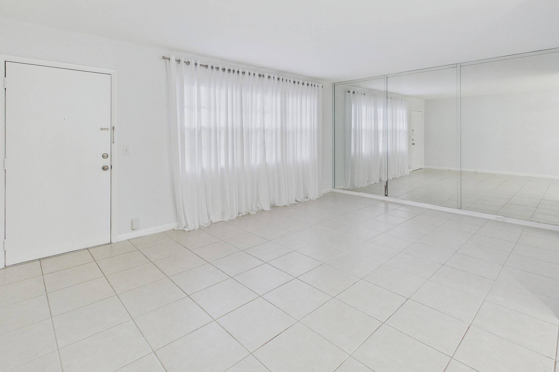 13155 SW 7TH Court, #103E, Pembroke Pines, FL 33027 White tile flooring, full-height mirrored wall, and a window with sheer white curtains.