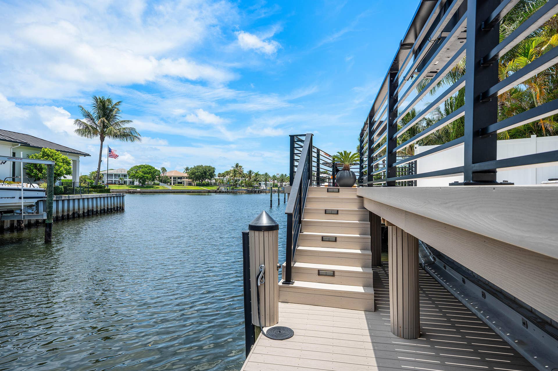 12898 S Shore Drive, Palm Beach Gardens, FL 33410 Waterfront property featuring a private dock with pilings, a boat lift, and a spacious deck with contemporary metal railings
