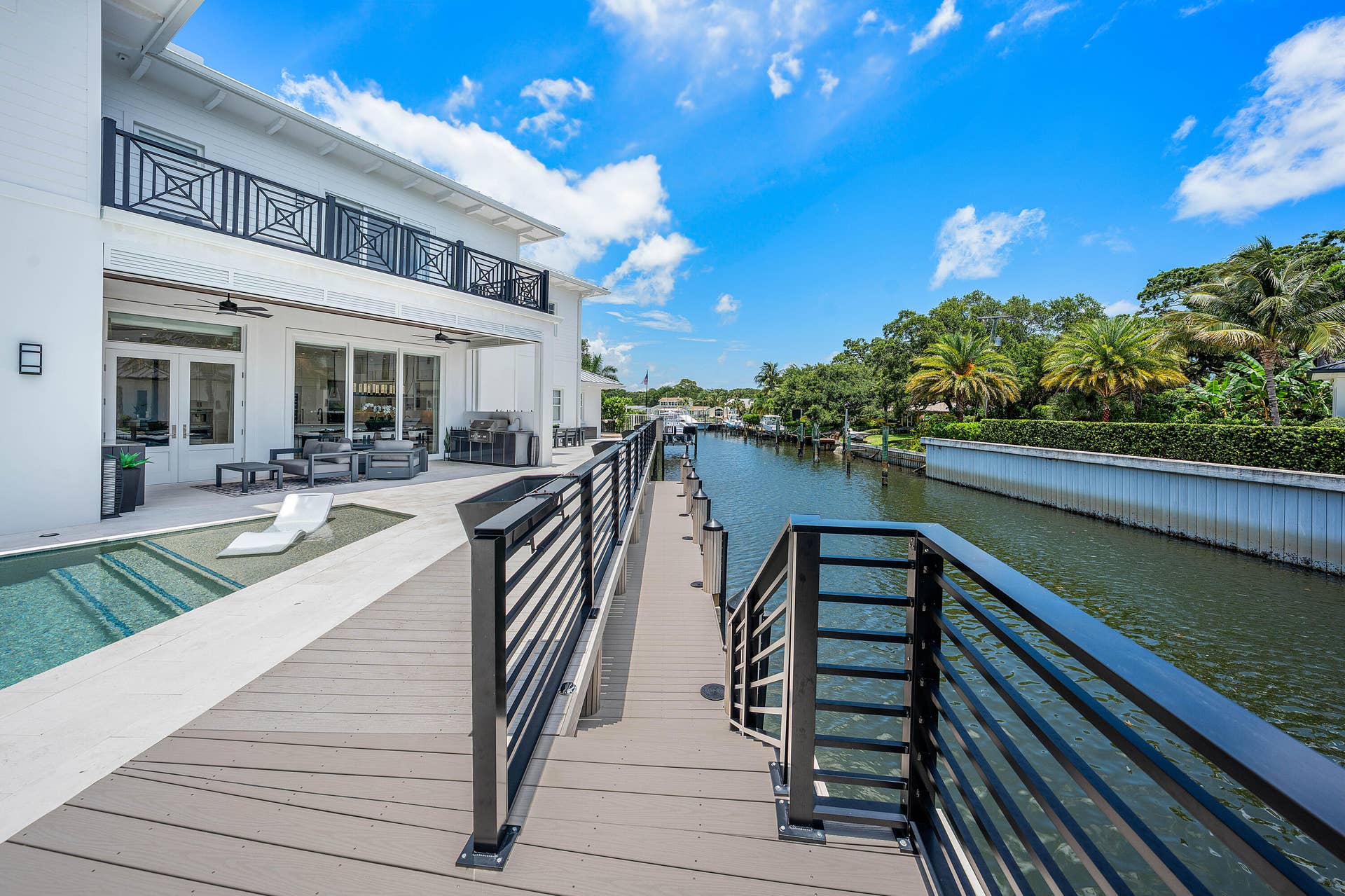 12898 S Shore Drive, Palm Beach Gardens, FL 33410 Waterfront property featuring a private dock with pilings, a boat lift, and a spacious deck with contemporary metal railings