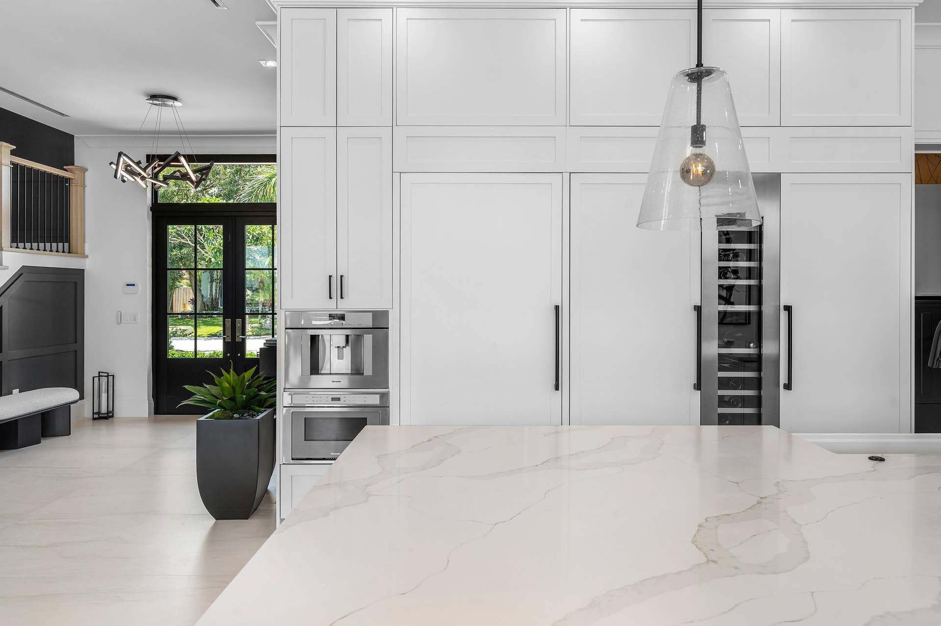 12898 S Shore Drive, Palm Beach Gardens, FL 33410 Integrated paneled refrigerators, built-in coffee system, wine refrigerator, expansive island with light-toned countertop, and double glass-paneled entry doors