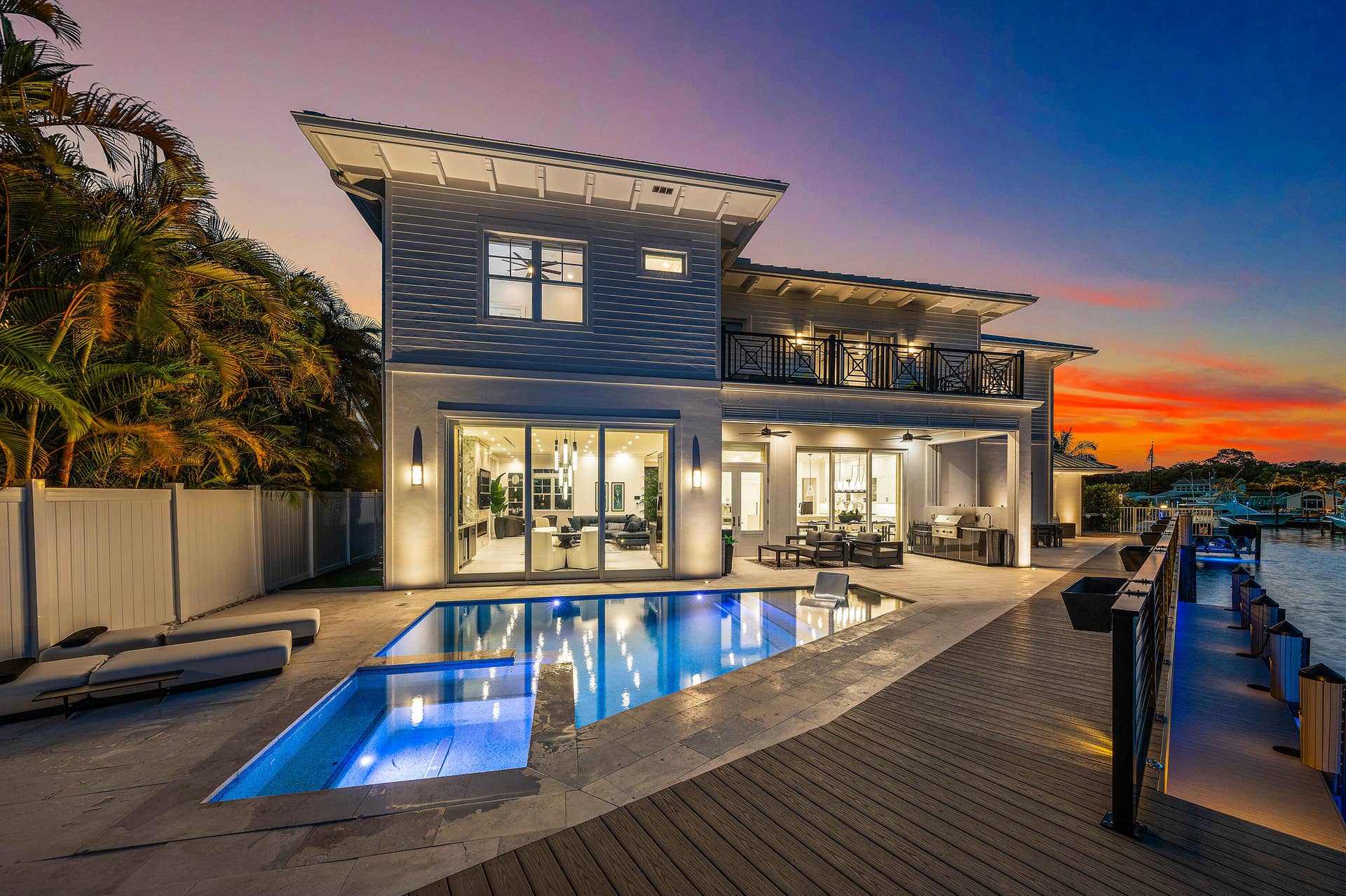 12898 S Shore Drive, Palm Beach Gardens, FL 33410 Contemporary exterior with a private swimming pool, expansive paved patio, and a wood-plank dock