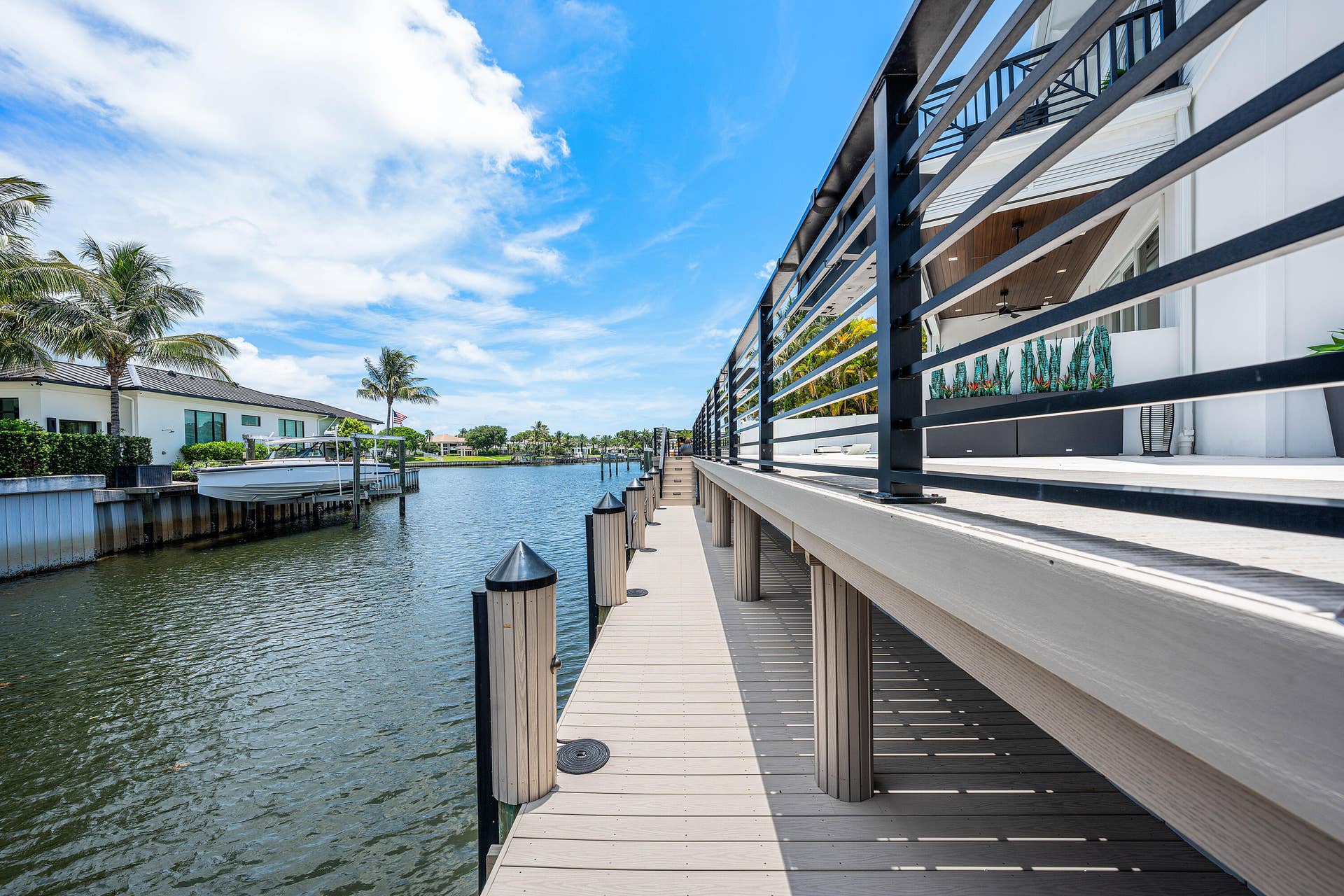 12898 S Shore Drive, Palm Beach Gardens, FL 33410 Waterfront property featuring a private dock with pilings, a boat lift, and a spacious deck with contemporary metal railings