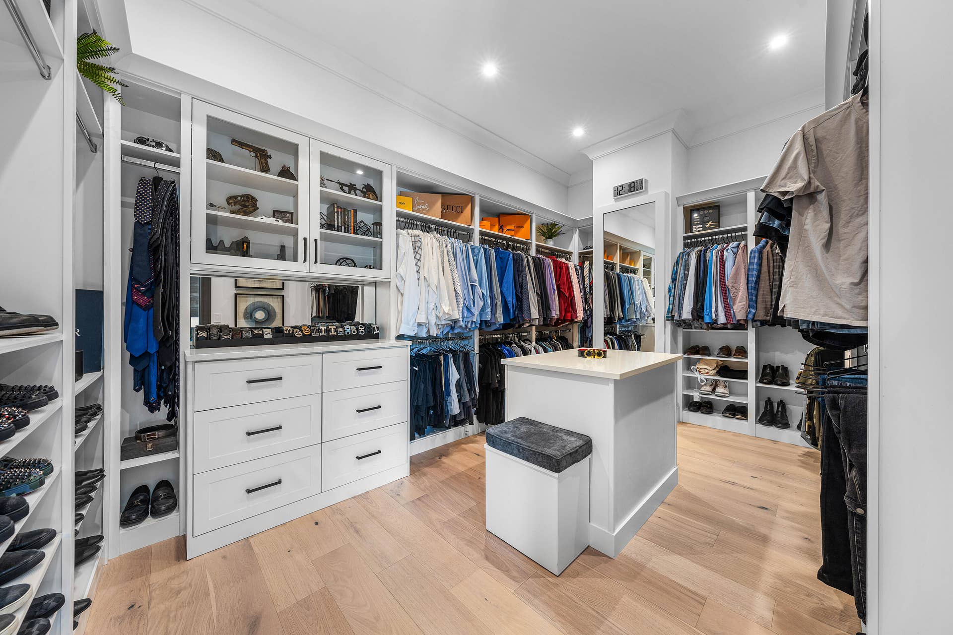 12898 S Shore Drive, Palm Beach Gardens, FL 33410 Custom closet system featuring built-in cabinetry, glass-front display cabinets, drawer storage, and an island with counter space