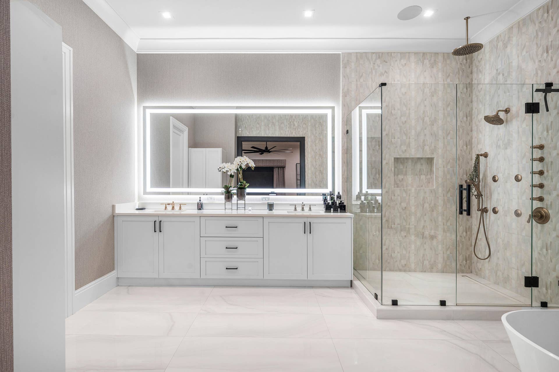 12898 S Shore Drive, Palm Beach Gardens, FL 33410 Spa-inspired primary bathroom featuring a dual-sink vanity with white cabinetry, polished quartz countertops, and integrated undermount sinks + large glass shower enclosure and modern mirror