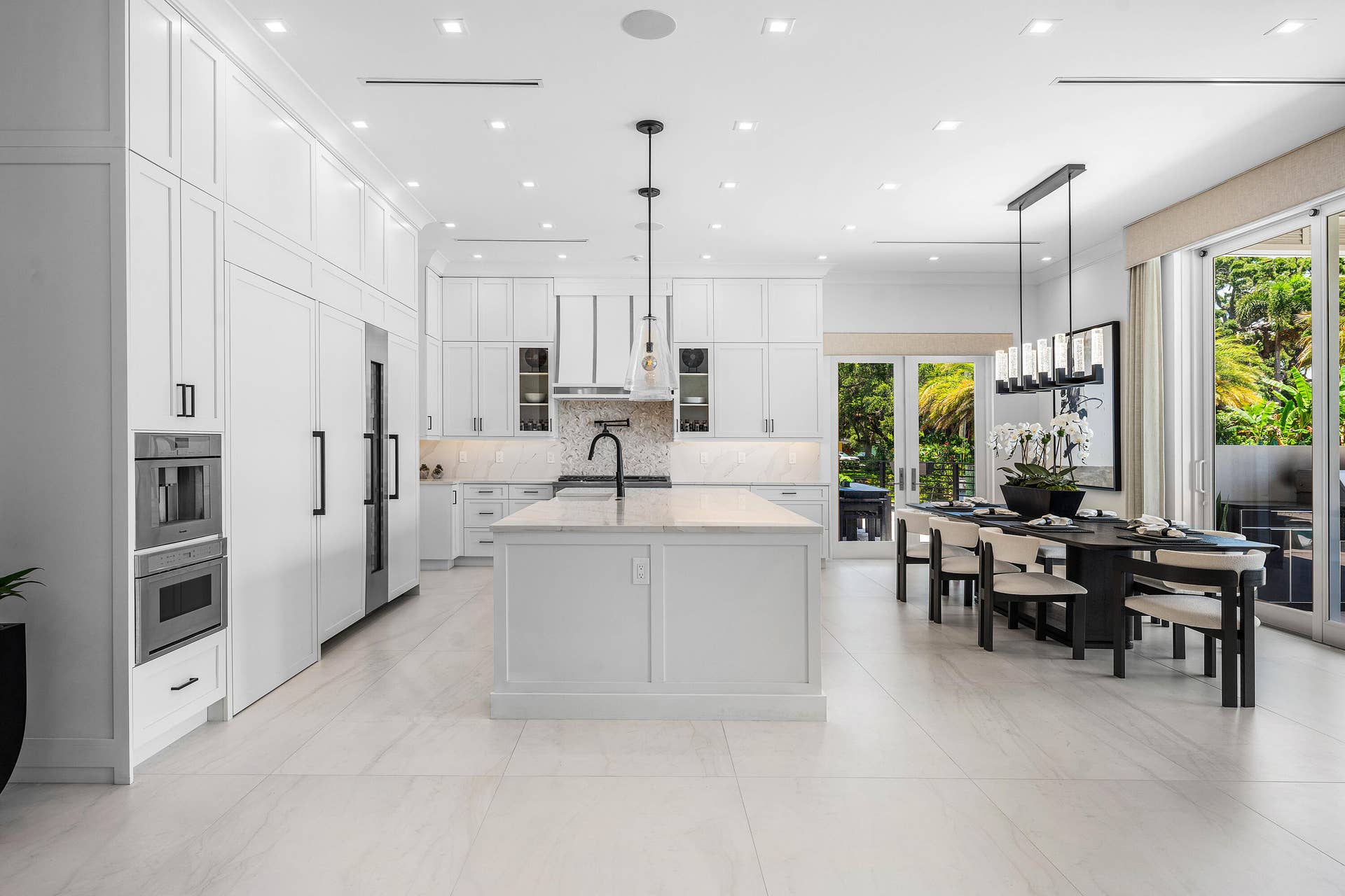 12898 S Shore Drive, Palm Beach Gardens, FL 33410 Gourmet kitchen featuring extensive white panel cabinetry, a large center island with countertop, integrated stainless steel appliances, and sleek tile flooring