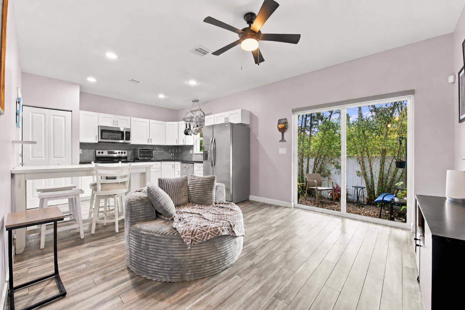 Open-concept kitchen and living area with wood-finish flooring, recessed lighting, and a ceiling fan