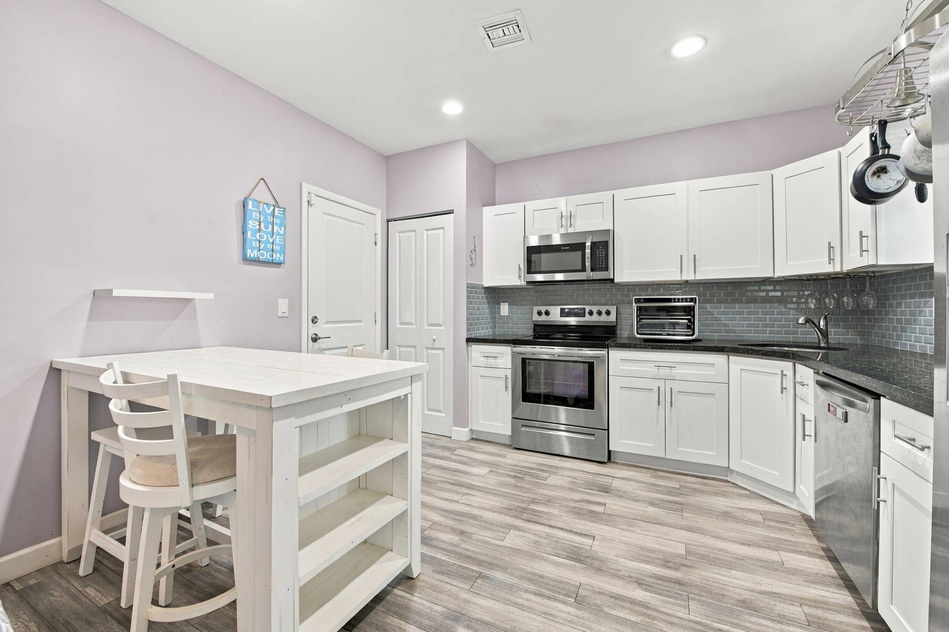White shaker cabinetry with stainless steel appliances, dark countertops, and a subway tile backsplash