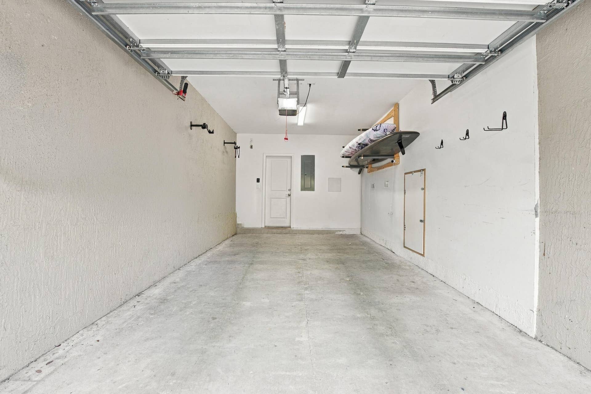 Spacious garage with concrete flooring, overhead lighting, and an interior access door