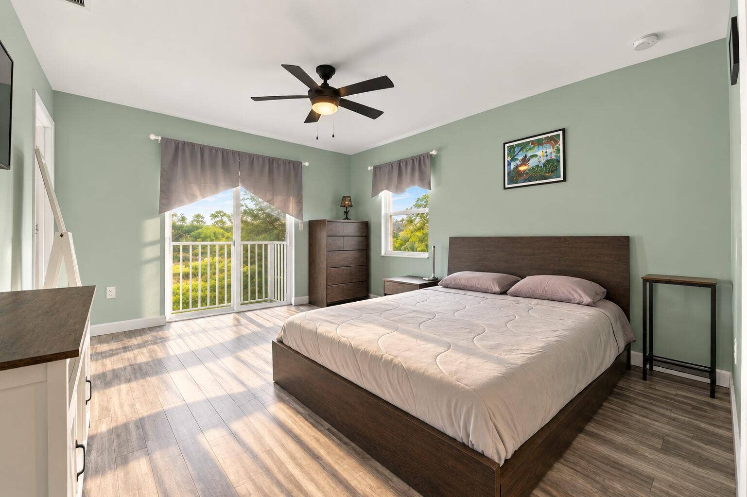 Wood-finish flooring, ceiling fan with integrated lighting, glass sliding door with balcony access, and natural light