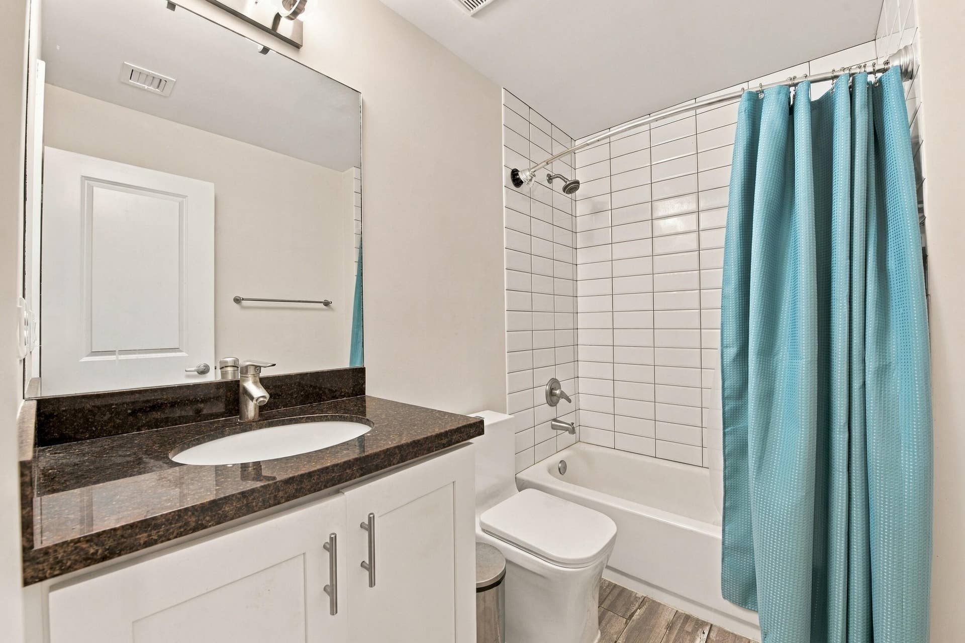 White vanity with brushed nickel hardware, dark stone countertop, undermount sink, and brushed nickel faucet
