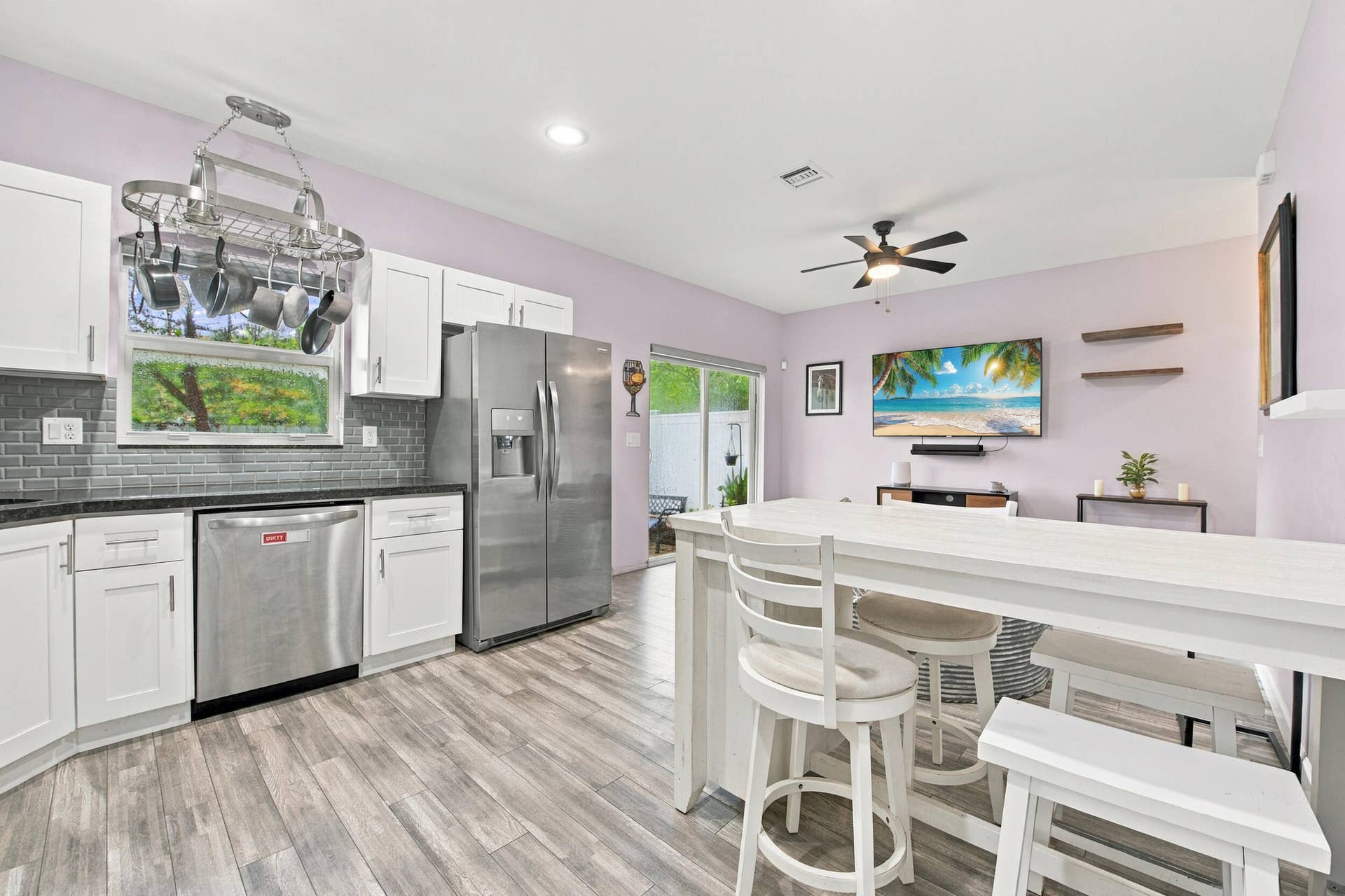 Kitchen featuring stainless steel appliances, white cabinetry, dark countertops, and a gray subway tile backsplash