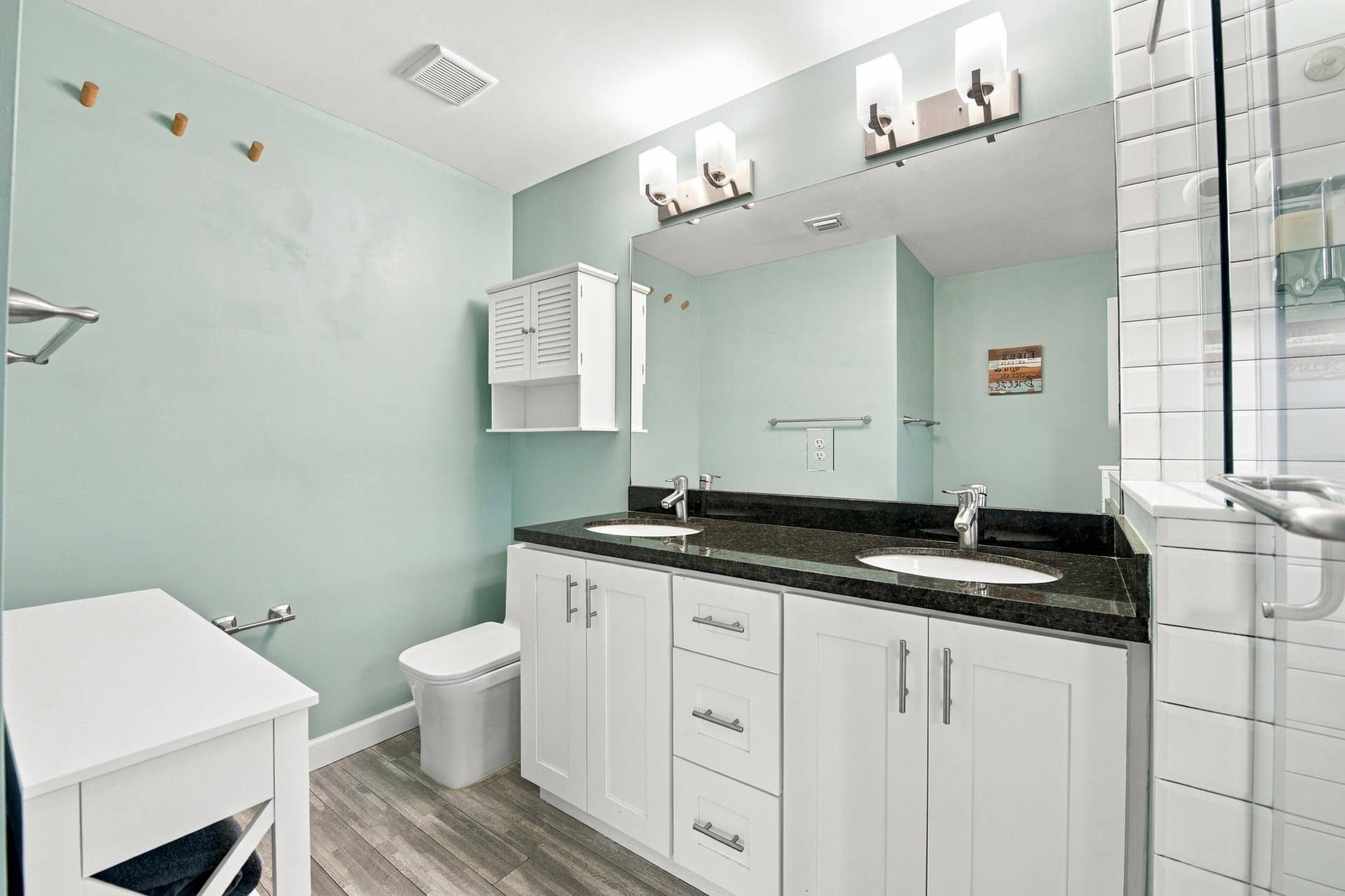 Dual vanity with dark stone countertop, white shaker cabinetry, and integrated sinks