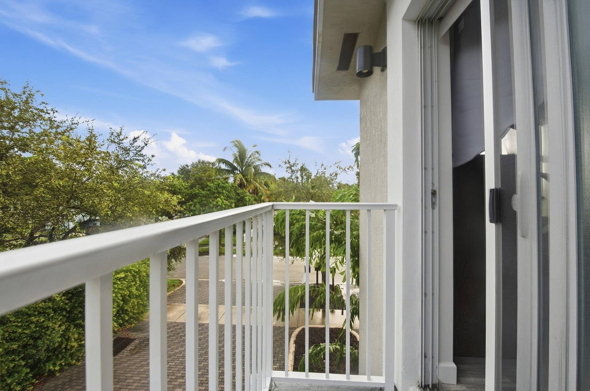 Balcony featuring a white metal railing, exterior wall sconce, and sliding glass door