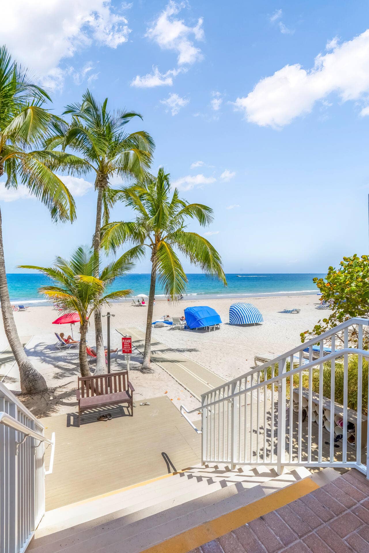 Direct beach access with a wide sandy expanse, mature palm trees, and ocean waters