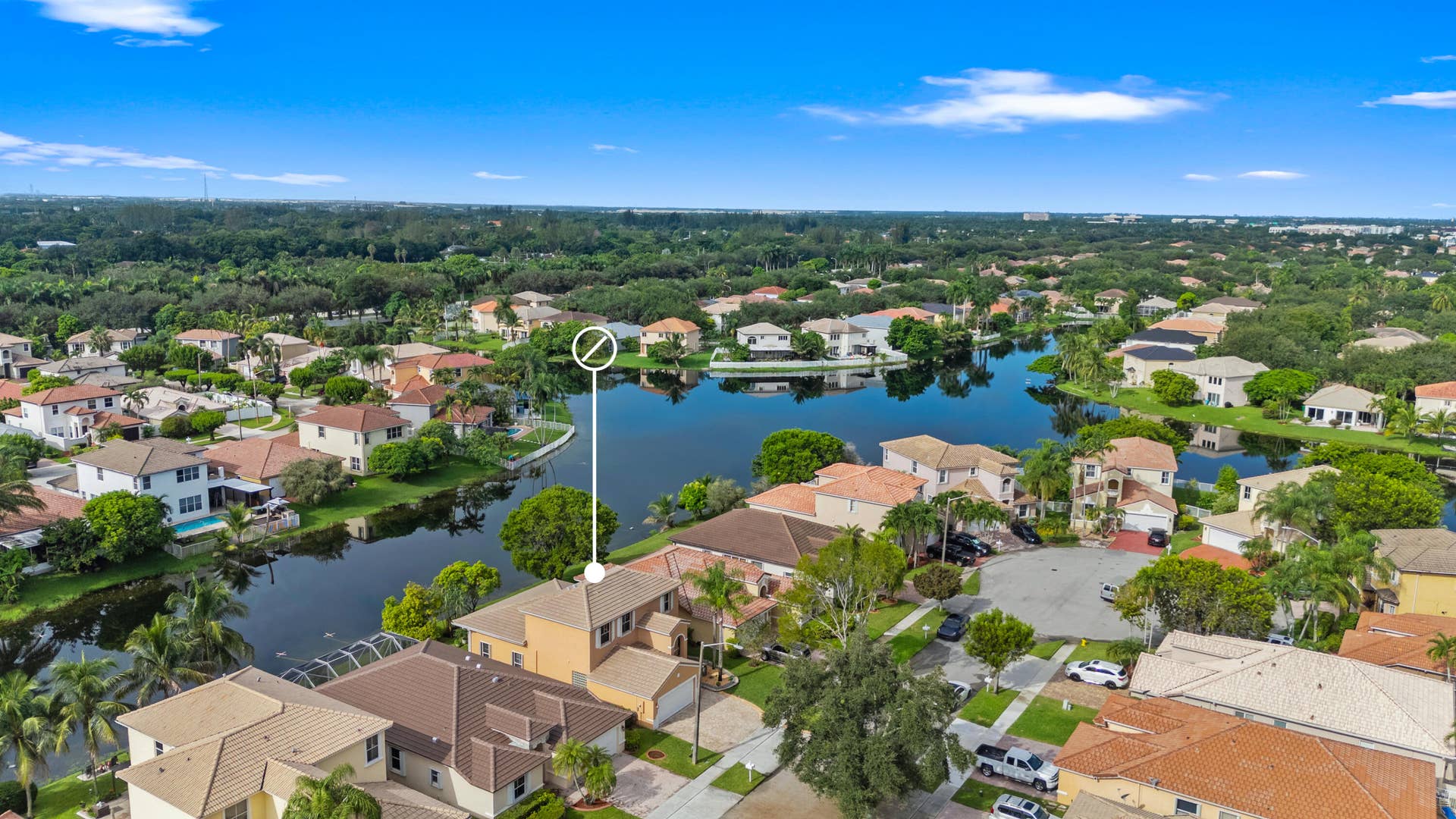 Aerial view emphasizing the homes position along the lake with surrounding waterfront residences and mature landscaping.