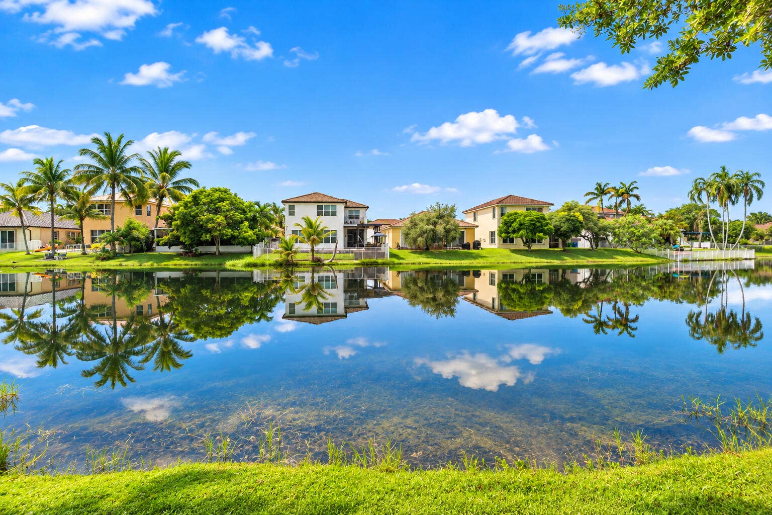 Wide lake views framed by mature trees and neighboring tropical landscaping.