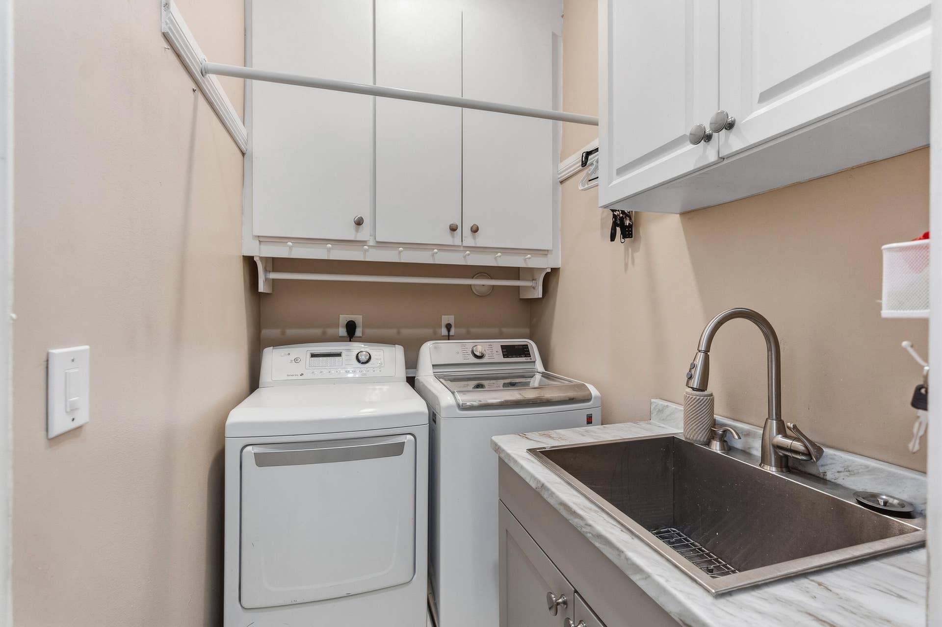 Well-equipped laundry room with updated washer and dryer, utility sink and abundant built-in cabinetry for added storage.