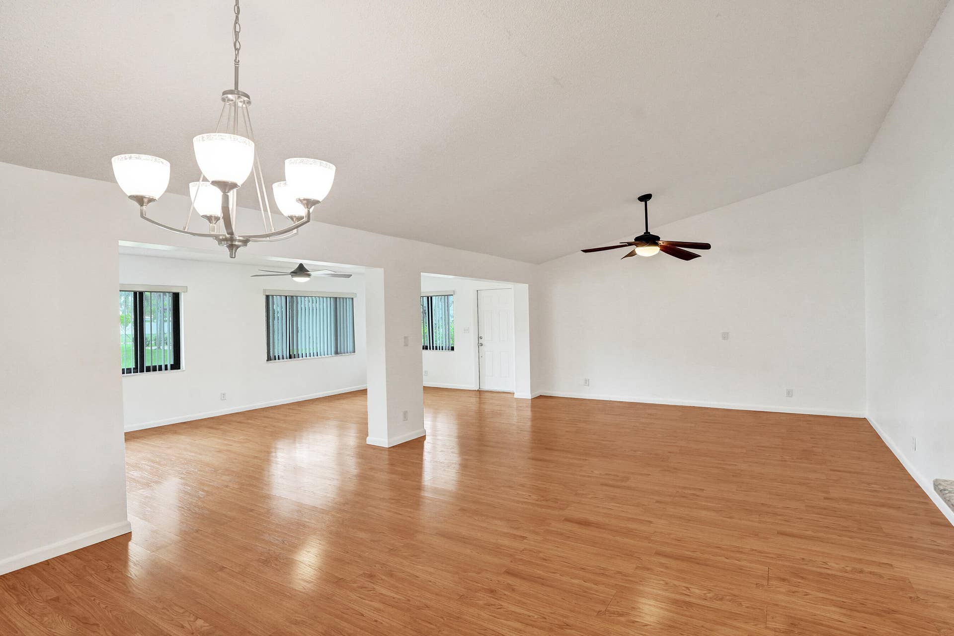 Vaulted ceiling with a ceiling fan, wood-finish flooring, recessed lighting, and multiple windows with vertical blinds