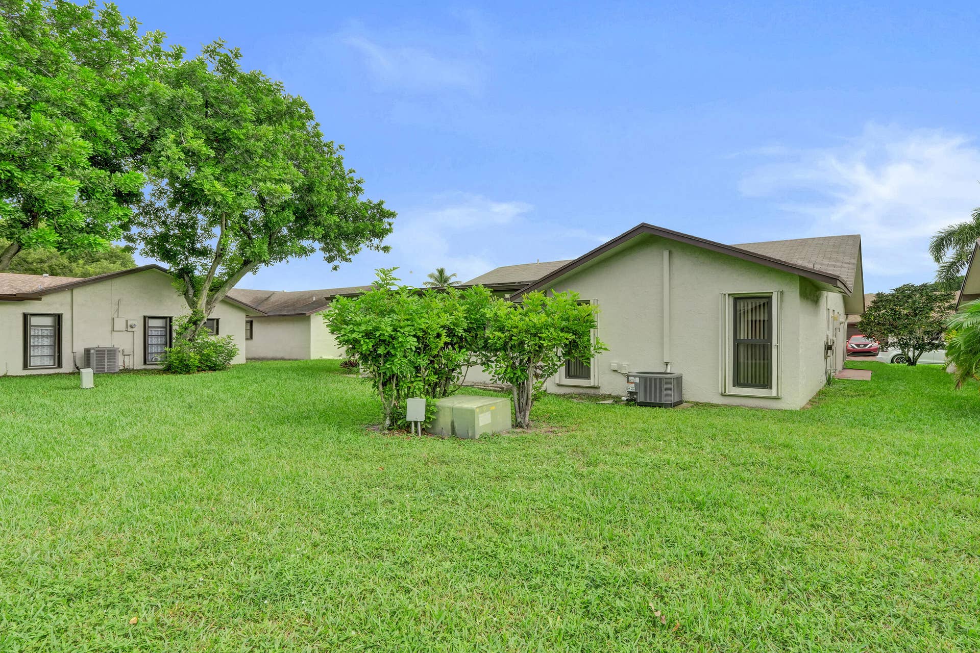 Expansive green lawn with mature trees and established perimeter shrubbery