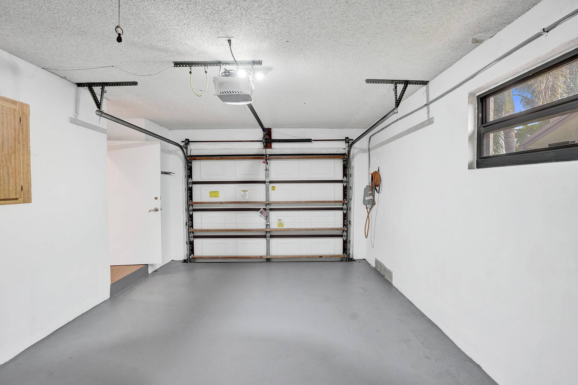 Attached garage with light gray flooring and a window