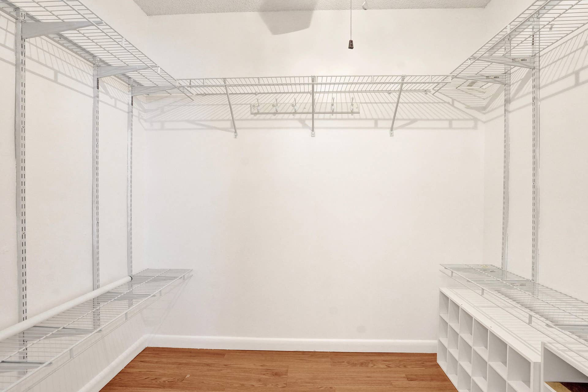 Integrated wire shelving system, built-in shoe cubbies, wood-finish flooring, and white baseboards