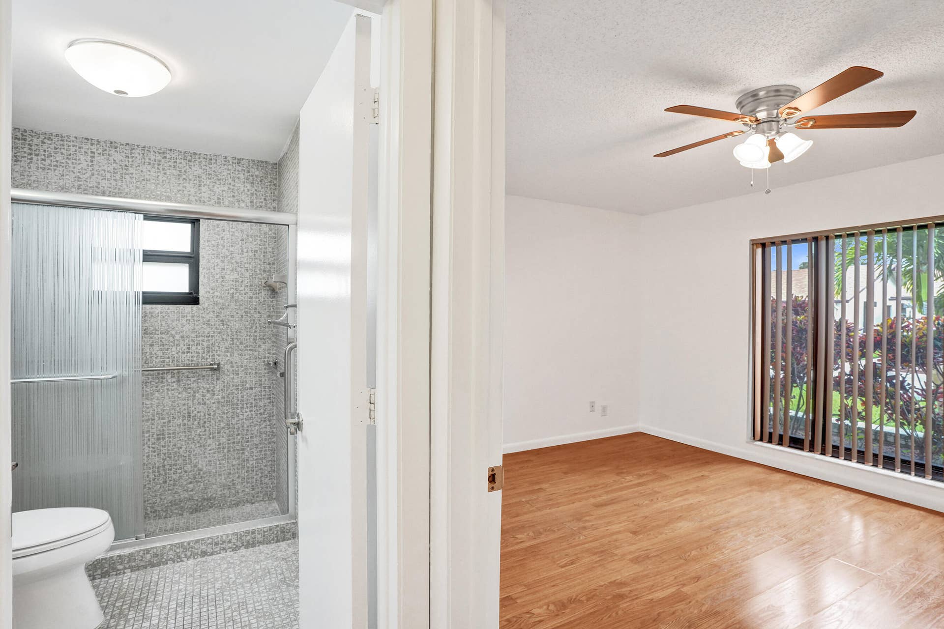 Bathroom featuring a shower with glass sliding doors, mosaic tile surround, and a fixed window